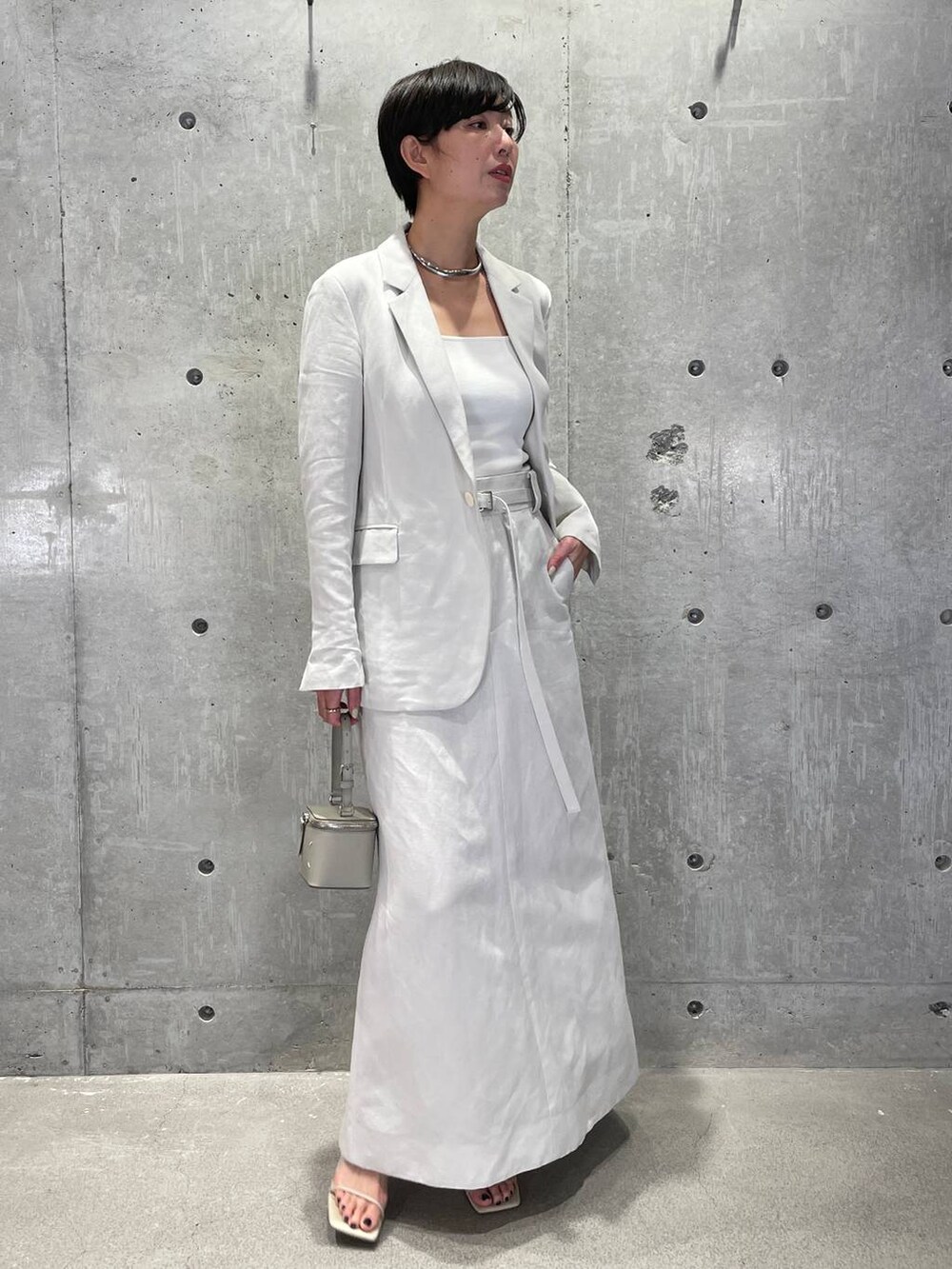 ホワイト系のタンクトップ、グレー系のベスト、ベージュ系のサンダルを着用したレディースの春コーディネートの3枚目の写真