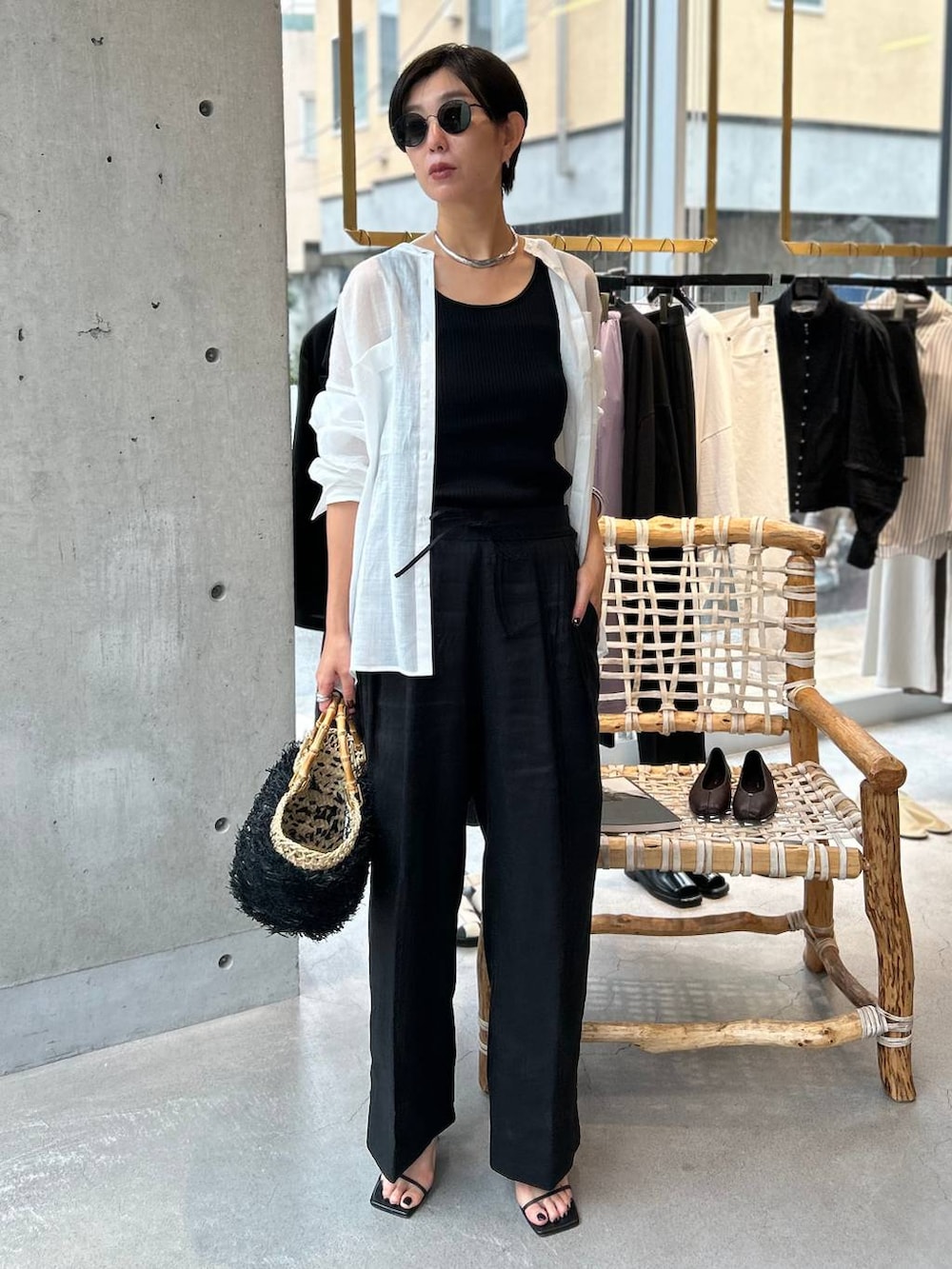 ブラック系のタンクトップ、ブラック系のかごバッグ、ブラック系のスラックスを着用したレディースの夏コーディネートの2枚目の写真