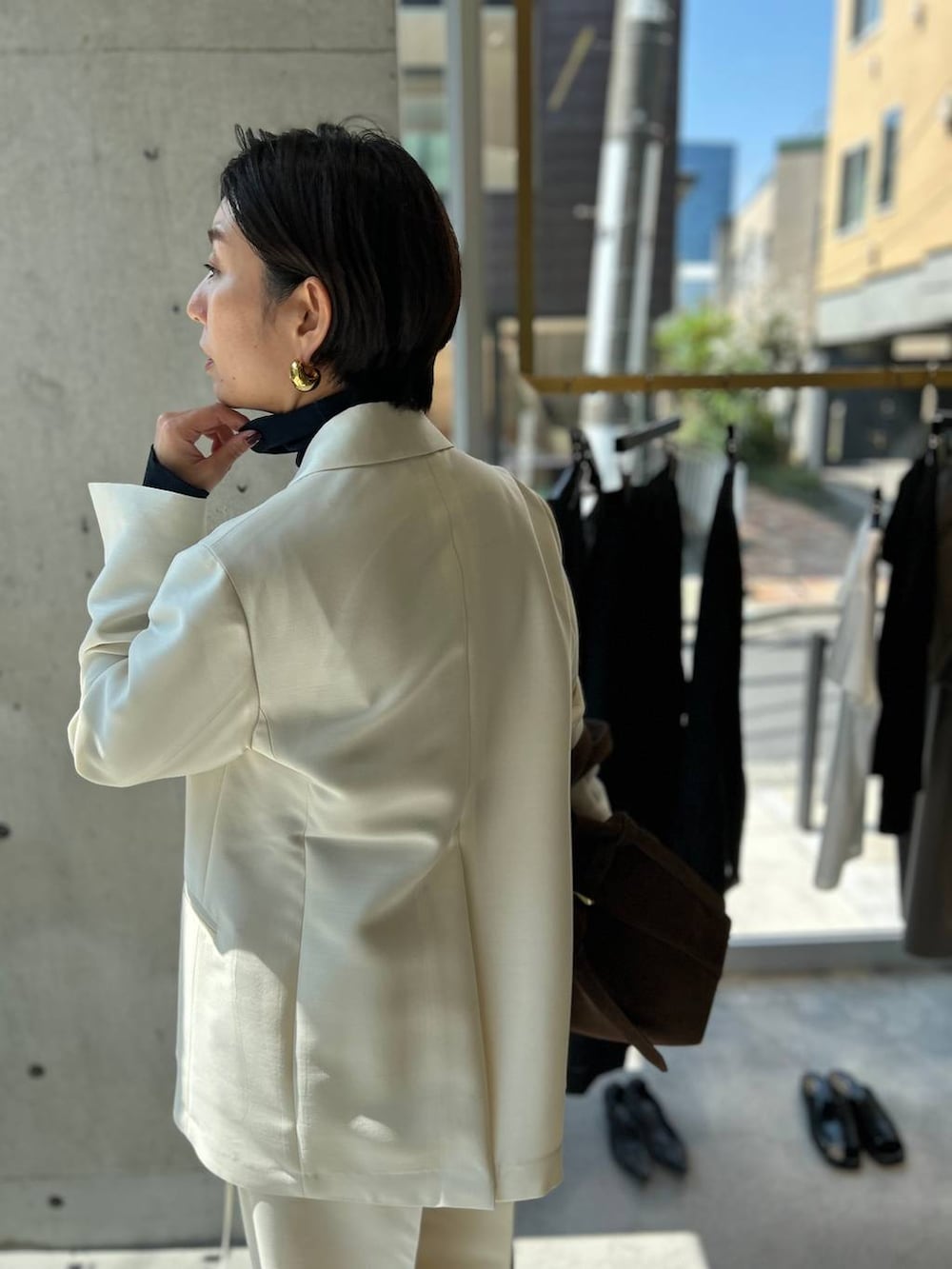 ブルー系のニット/セーター、ブラウン系のノーカラーコート、ホワイト系のテーラードジャケットを着用したレディースの秋コーディネートの7枚目の写真