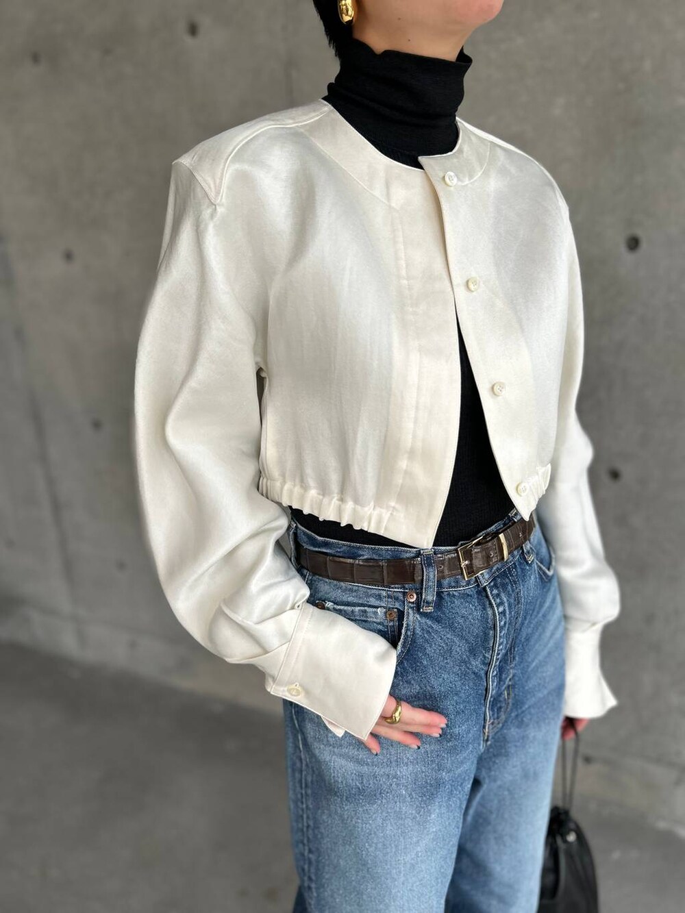 ブラック系のニット/セーター、ブルー系のデニムパンツ、ホワイト系のシャツ/ブラウスを着用したレディースの冬コーディネートの6枚目の写真