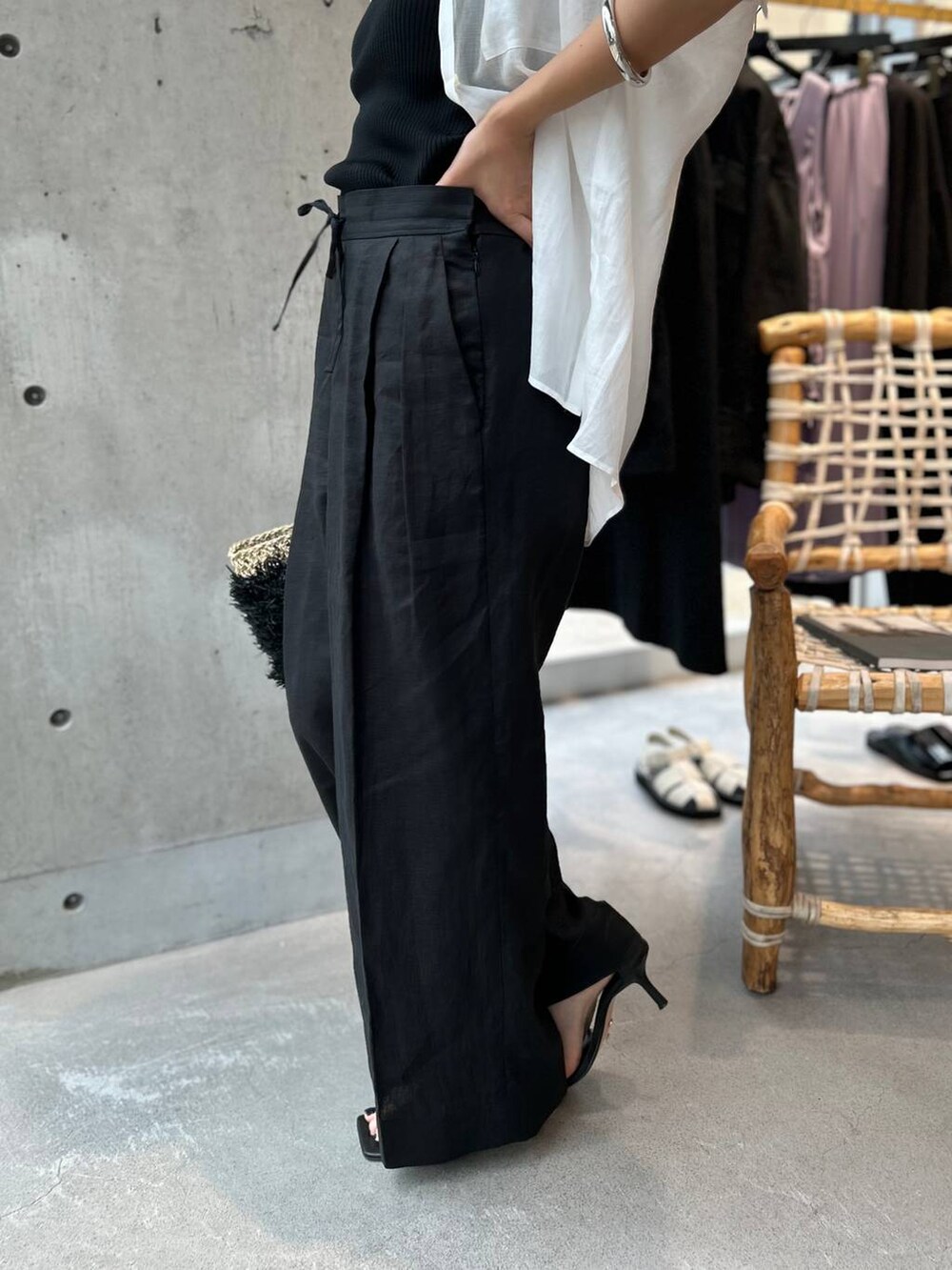 ブラック系のタンクトップ、ブラック系のかごバッグ、ブラック系のスラックスを着用したレディースの夏コーディネートの9枚目の写真