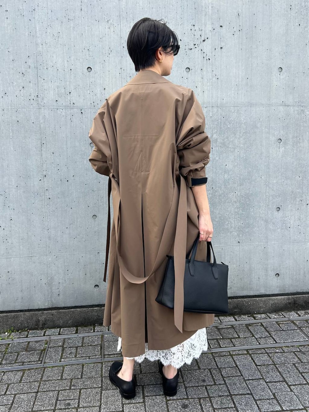 ブラック系のニット/セーター、ベージュ系のトレンチコートを着用したレディースの冬コーディネートの4枚目の写真