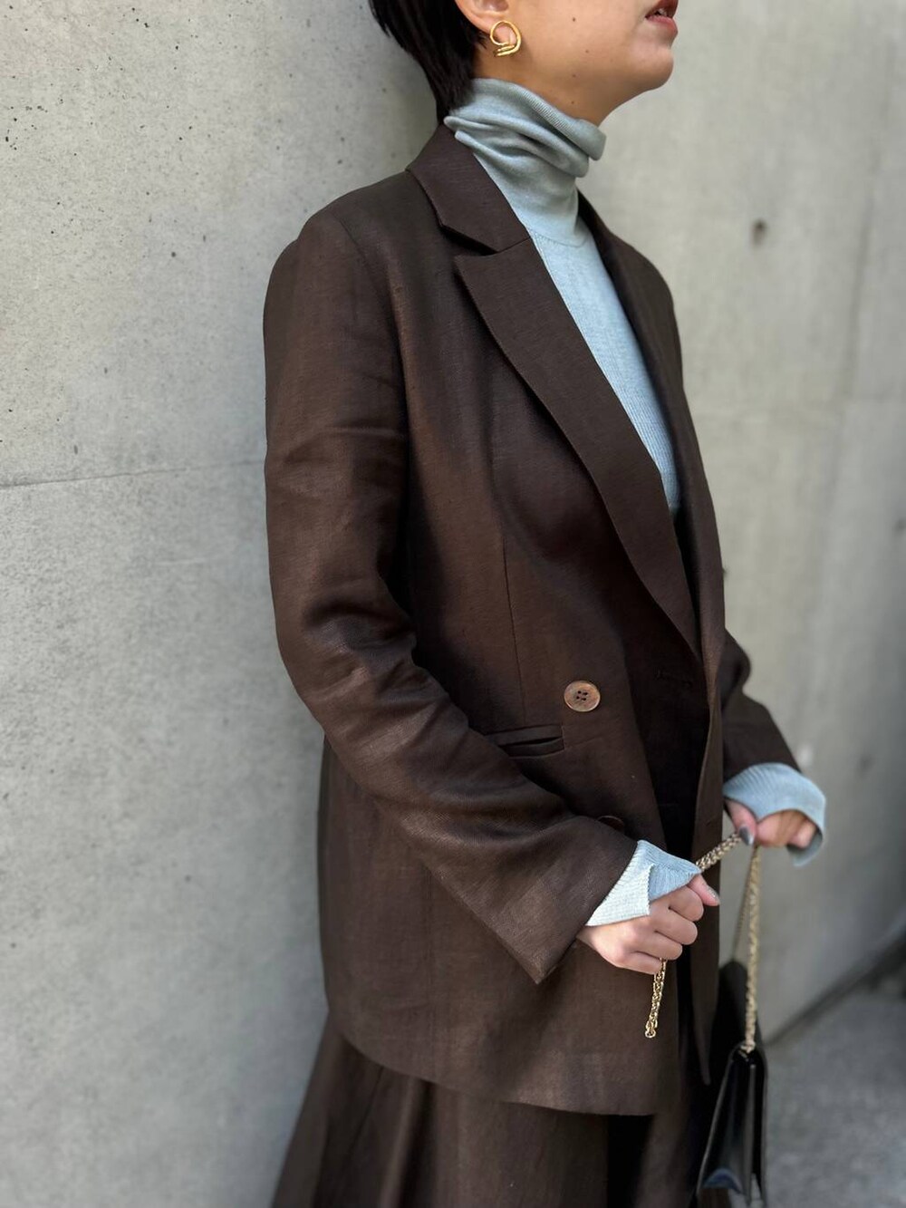 ブルー系のニット/セーター、ブラウン系のテーラードジャケット、ブラウン系のスカートを着用したレディースの冬コーディネートの6枚目の写真