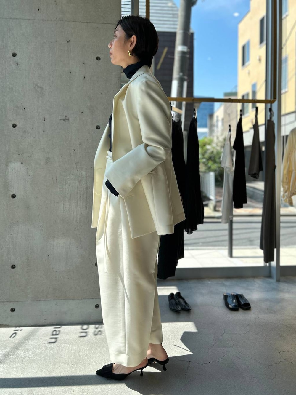 ブルー系のニット/セーター、ブラウン系のノーカラーコート、ホワイト系のテーラードジャケットを着用したレディースの秋コーディネートの4枚目の写真