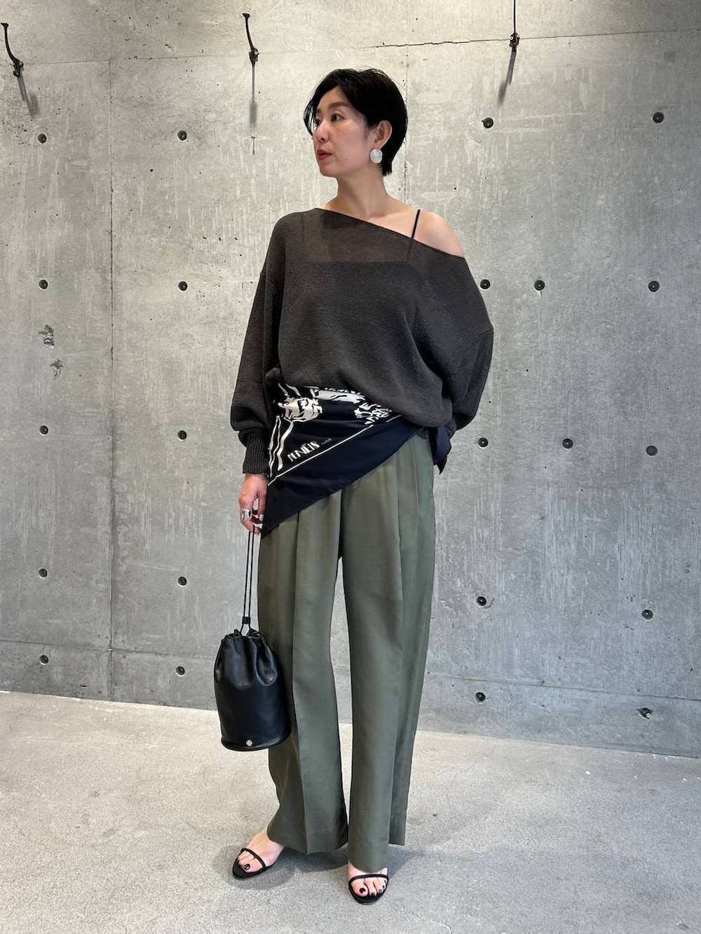 ブラック系のチューブトップ、グリーン系のニット/セーター、グリーン系のスラックスを着用したレディースの春コーディネートの2枚目の写真