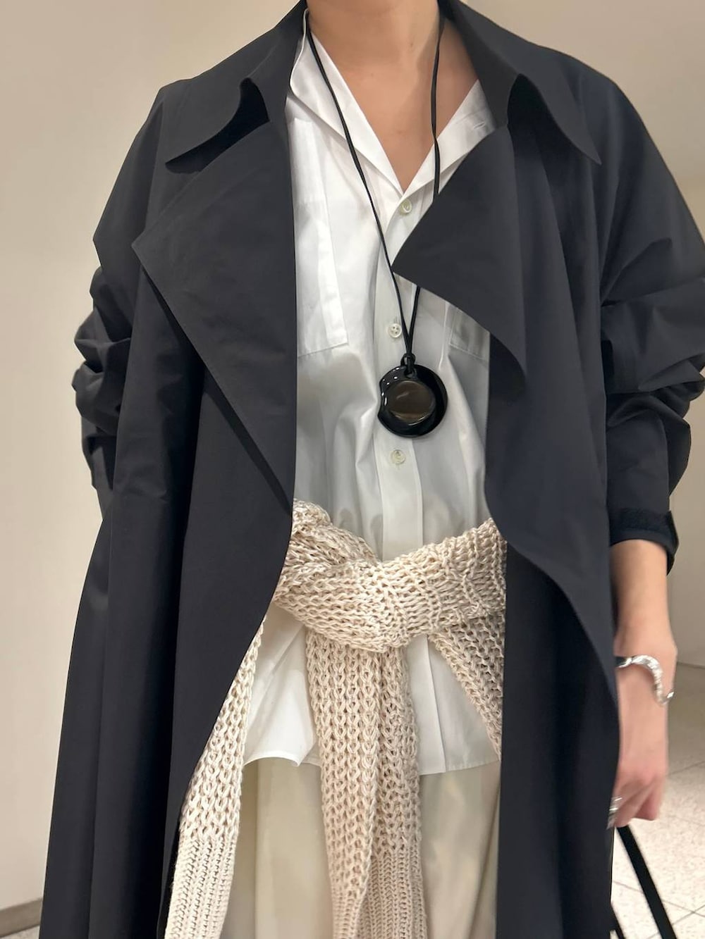 ホワイト系のニット/セーター、ホワイト系のシャツ/ブラウス、ブラック系のトレンチコートを着用したレディースの冬コーディネートの5枚目の写真