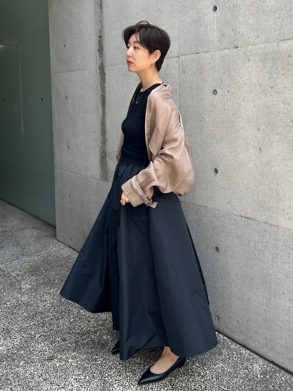 グレー系のブルゾン、ブラック系のスカート、ブラウン系のニット/セーターを着用したレディースの春コーディネートの3枚目の写真