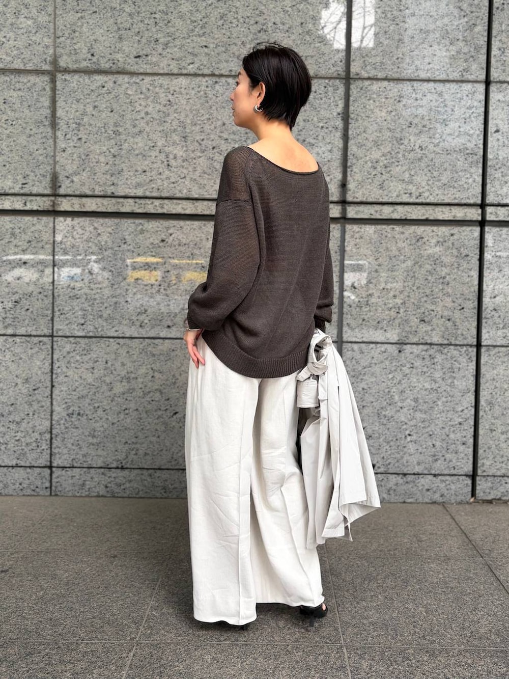 グリーン系のニット/セーター、ホワイト系のスラックス、グレー系のナイロンジャケットを着用したレディースの春コーディネートの6枚目の写真