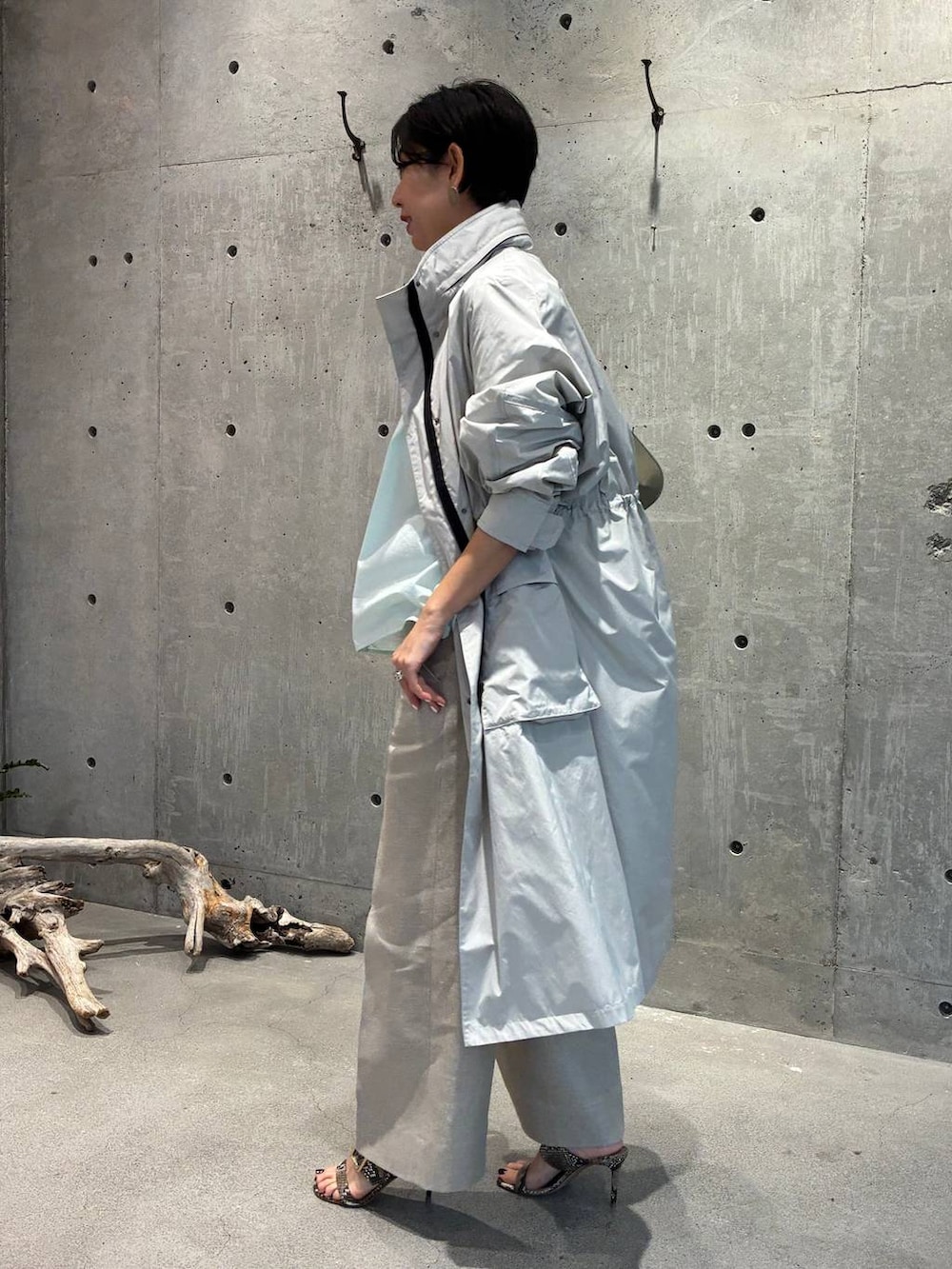 ホワイト系のスラックス、グレー系のナイロンジャケットを着用したレディースの春コーディネートの2枚目の写真