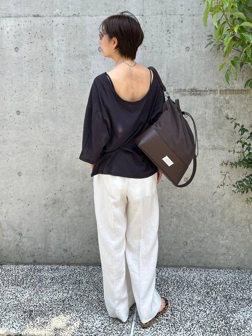ブラック系のチューブトップ、ホワイト系のスラックス、グレー系のTシャツ/カットソーを着用したレディースの春コーディネートの4枚目の写真