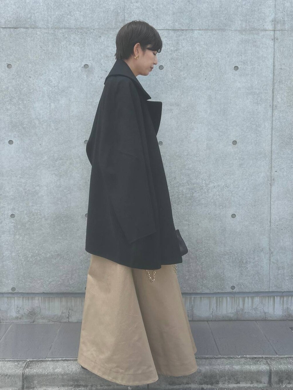 オレンジ系のTシャツ/カットソー、ベージュ系のスカート、ブラック系のその他アウターを着用したレディースの秋コーディネートの3枚目の写真