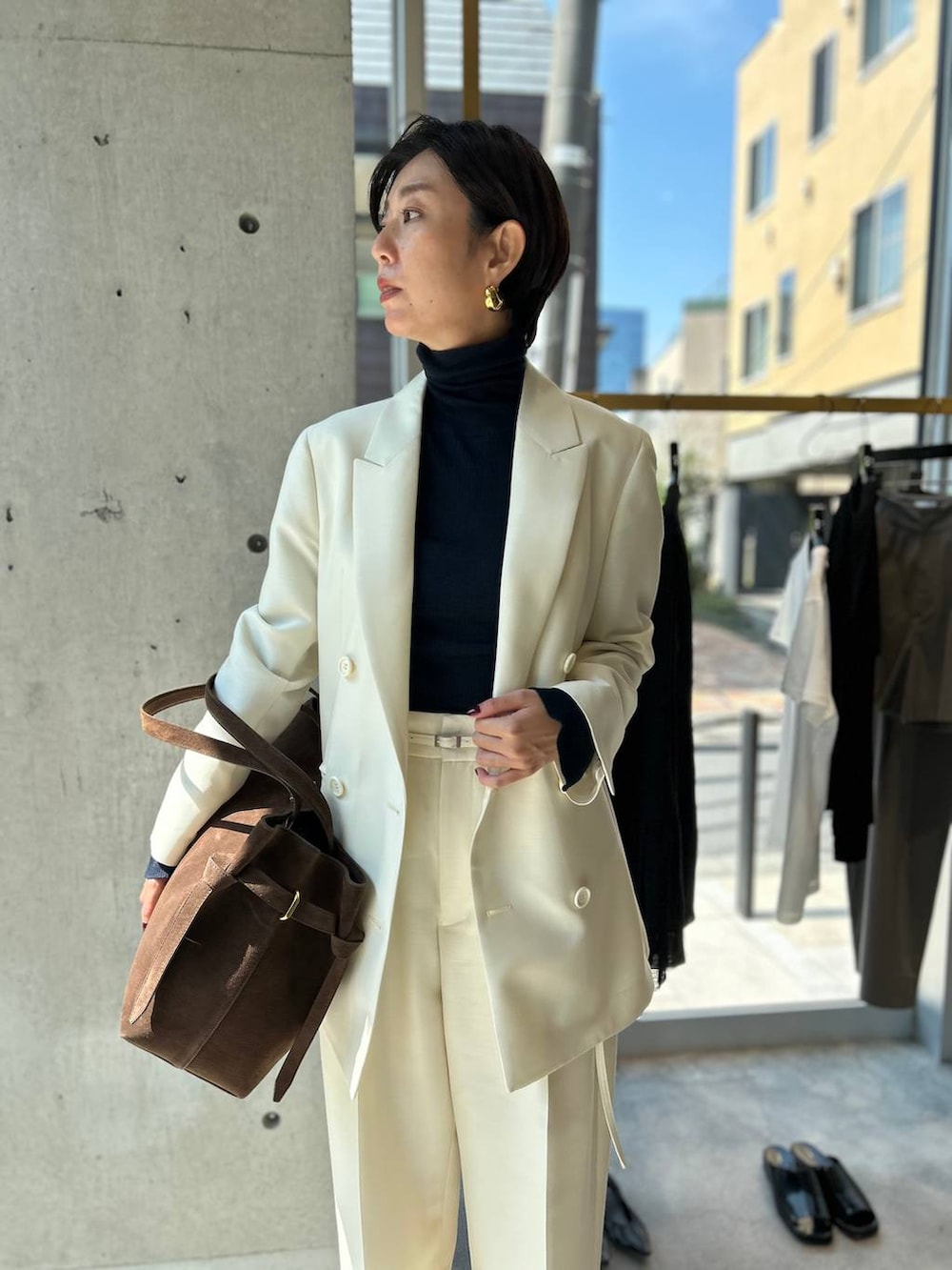 ブルー系のニット/セーター、ブラウン系のノーカラーコート、ホワイト系のテーラードジャケットを着用したレディースの秋コーディネートの6枚目の写真