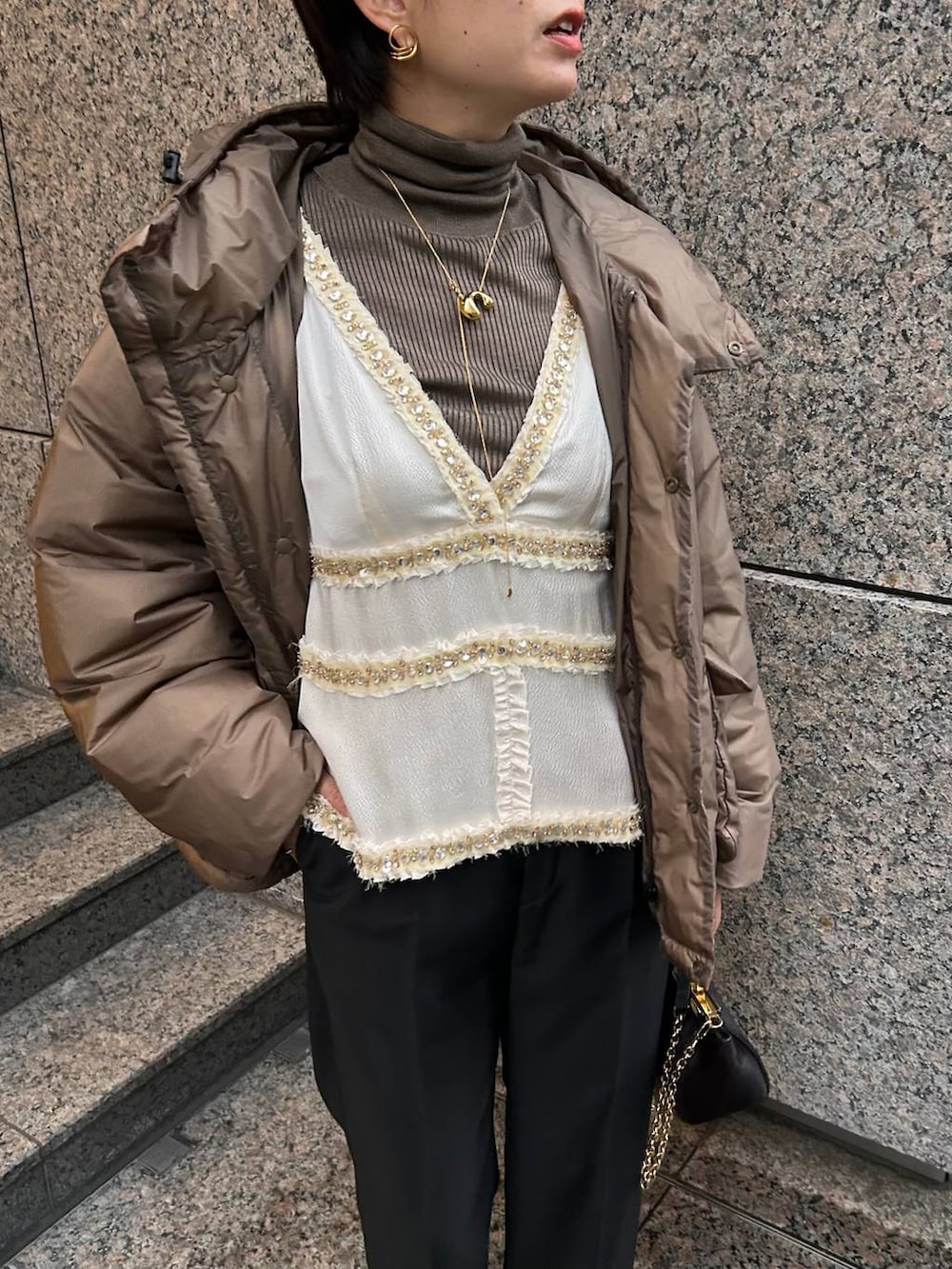 ベージュ系のニット/セーター、ブラウン系のダウンジャケット/コート、ブラック系のスラックスを着用したレディースの冬コーディネートの6枚目の写真