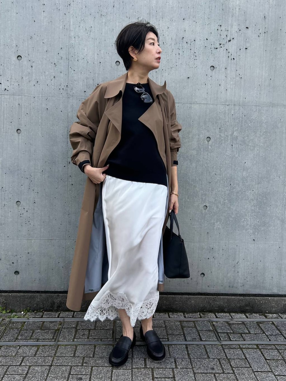 ブラック系のニット/セーター、ベージュ系のトレンチコートを着用したレディースの冬コーディネートの2枚目の写真
