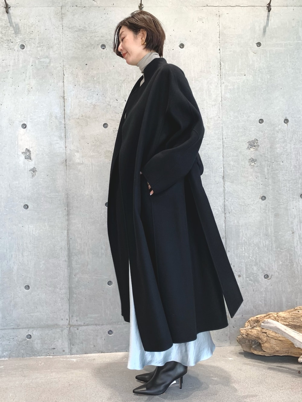 ブラック系のジャケット/アウター、ベージュ系のニット/セーター、グリーン系のスカートを着用したレディースの秋コーディネートの2枚目の写真