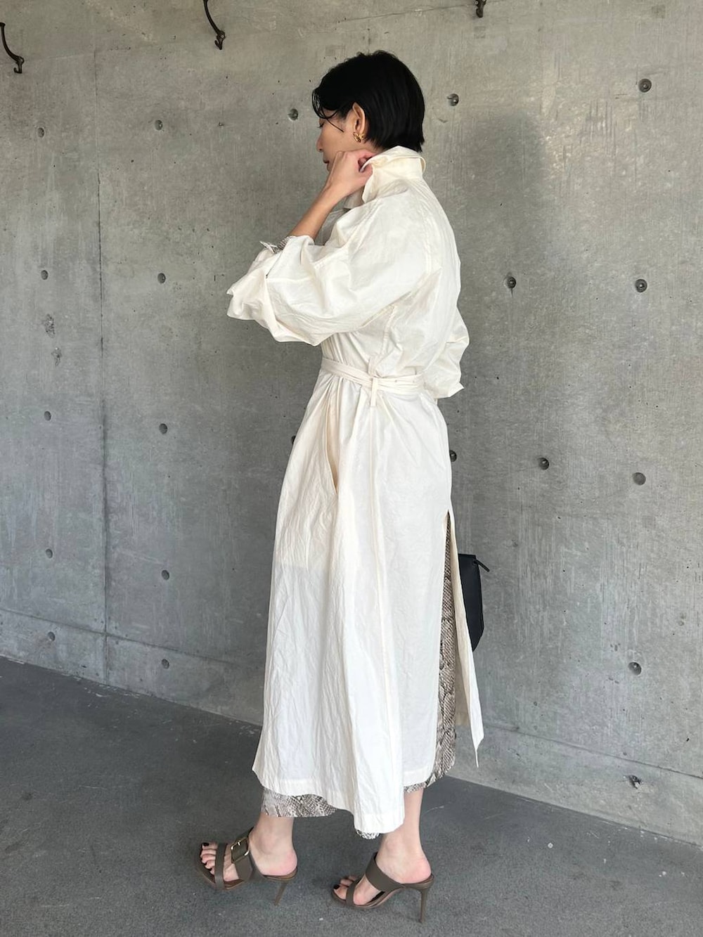 ホワイト系のステンカラーコート、ベージュ系のワンピースを着用したレディースの春コーディネートの3枚目の写真