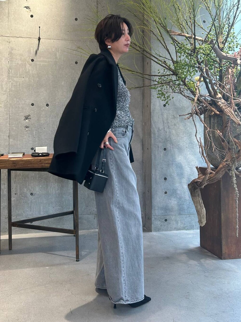 グレー系のデニムパンツ、ブラック系のピーコート、シルバー系のニット/セーターを着用したレディースの秋コーディネートの2枚目の写真