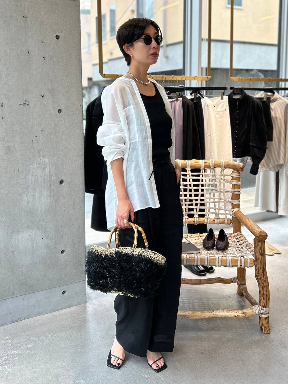 ブラック系のタンクトップ、ブラック系のかごバッグ、ブラック系のスラックスを着用したレディースの夏コーディネートの3枚目の写真