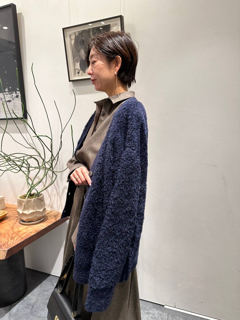 ブルー系のカーディガン/ボレロ、ブラック系のブーツ、ブラウン系のスカートを着用したレディースの冬コーディネートの2枚目の写真