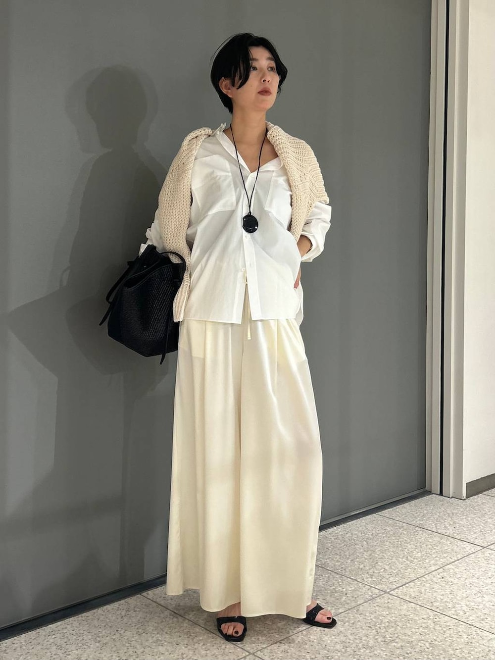 ホワイト系のニット/セーター、ホワイト系のシャツ/ブラウス、ブラック系のトレンチコートを着用したレディースの冬コーディネートの6枚目の写真