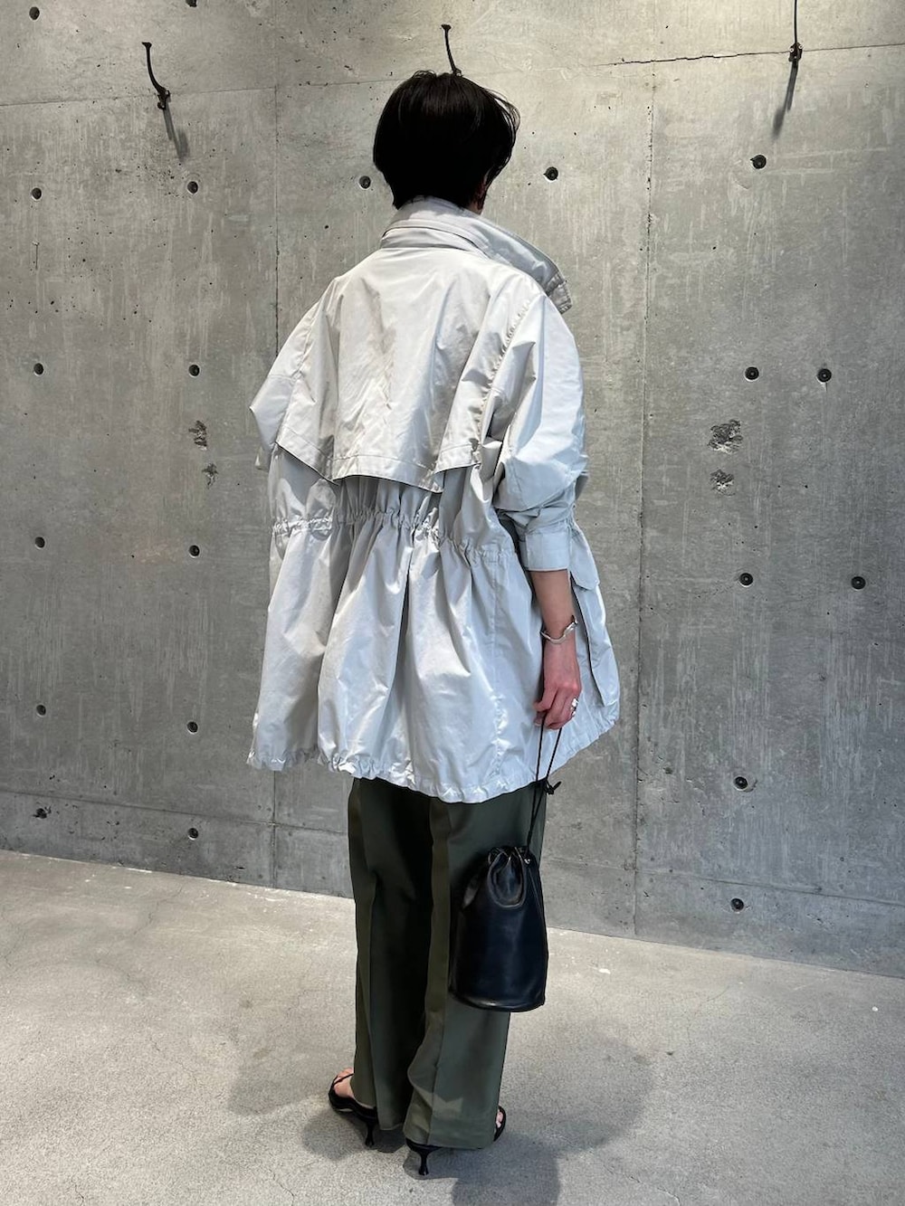 ブラック系のチューブトップ、グリーン系のニット/セーター、グリーン系のスラックスを着用したレディースの春コーディネートの9枚目の写真