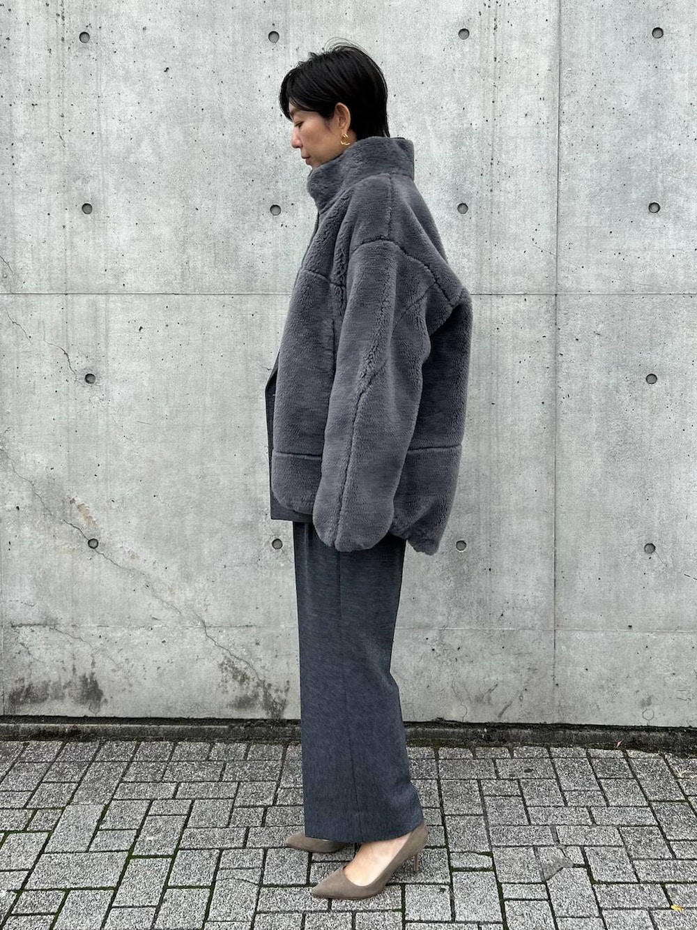 ブラック系のニット/セーター、グレー系のブルゾン、ホワイト系のスラックスを着用したレディースの秋コーディネートの2枚目の写真