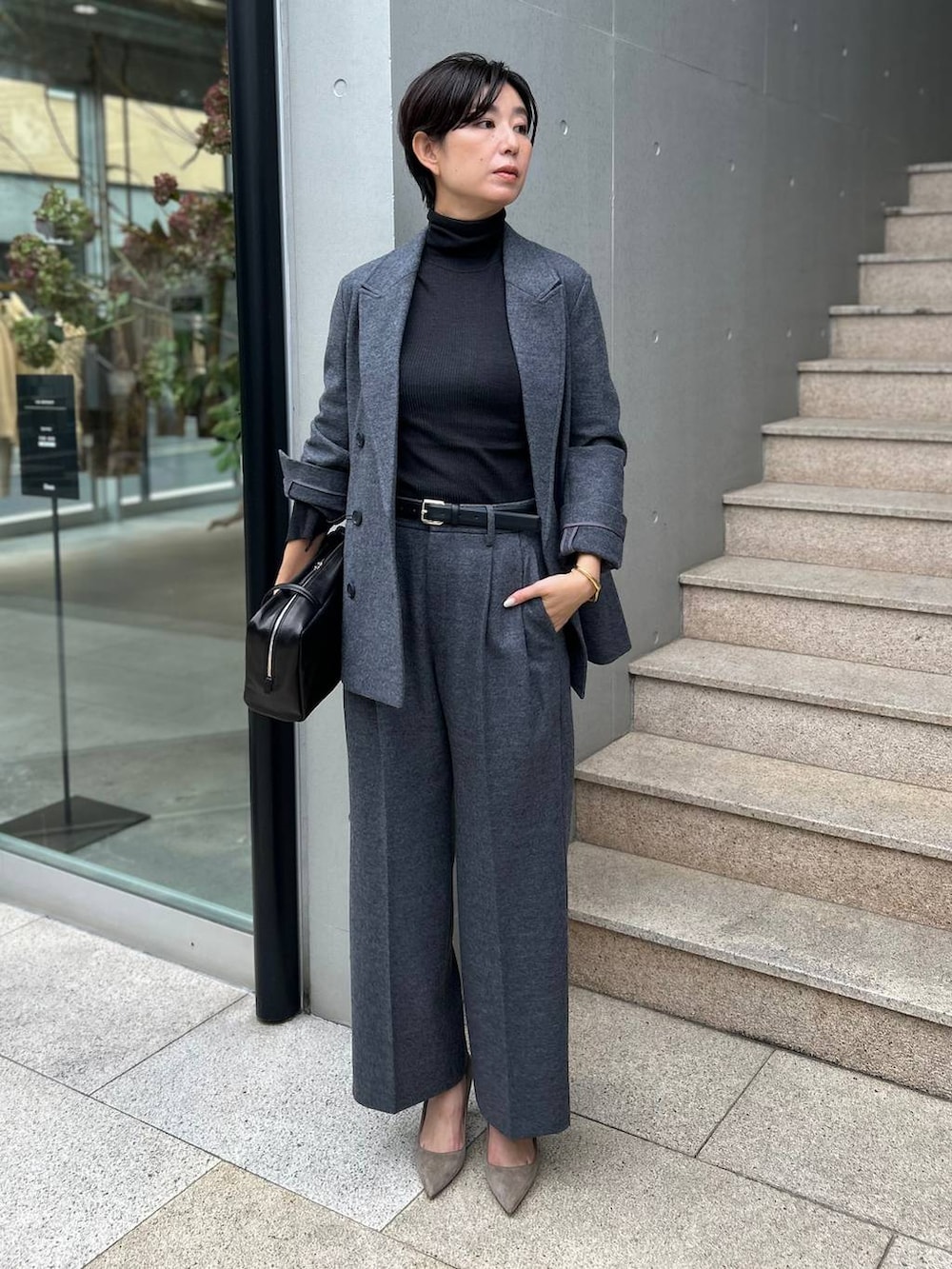 ブラック系のニット/セーター、グレー系のブルゾン、ホワイト系のスラックスを着用したレディースの秋コーディネートの5枚目の写真