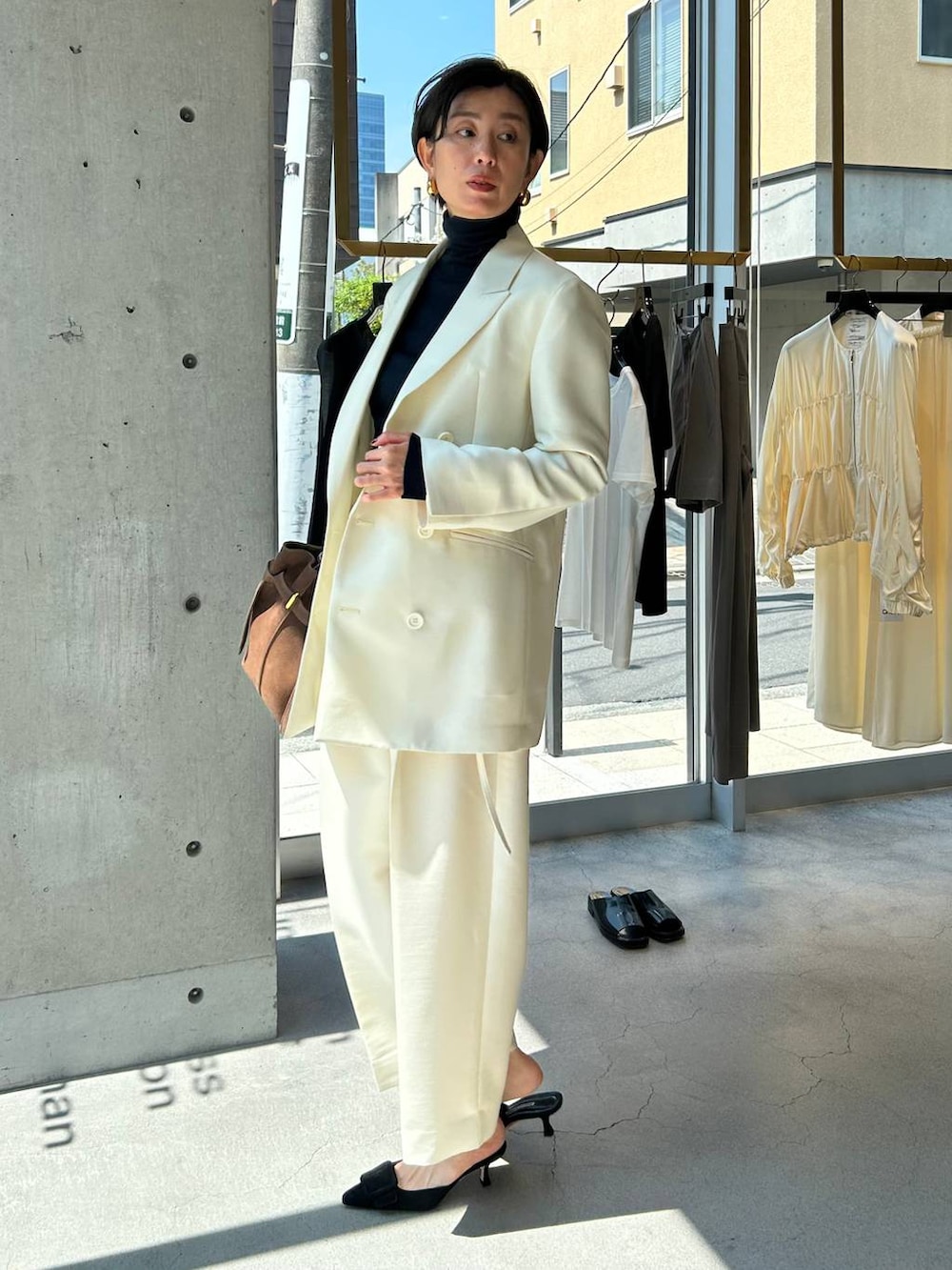 ブルー系のニット/セーター、ブラウン系のノーカラーコート、ホワイト系のテーラードジャケットを着用したレディースの秋コーディネートの3枚目の写真