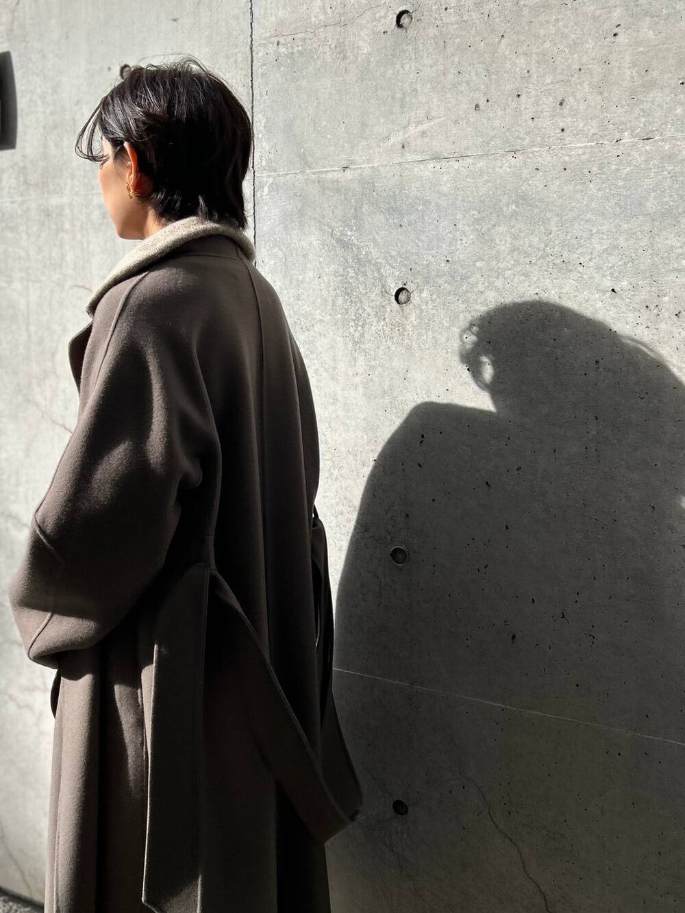 ブラウン系のノーカラーコート、ホワイト系のその他パンツ、ベージュ系のニット/セーターを着用したレディースの冬コーディネートの7枚目の写真