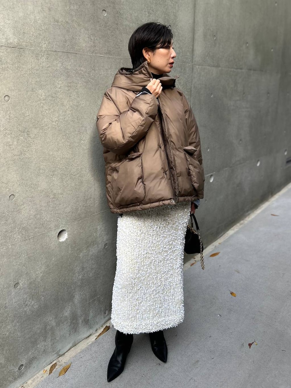 ブラック系のニット/セーター、ブルー系のシャツ/ブラウス、ブラウン系のダウンジャケット/コートを着用したレディースの冬コーディネートの2枚目の写真