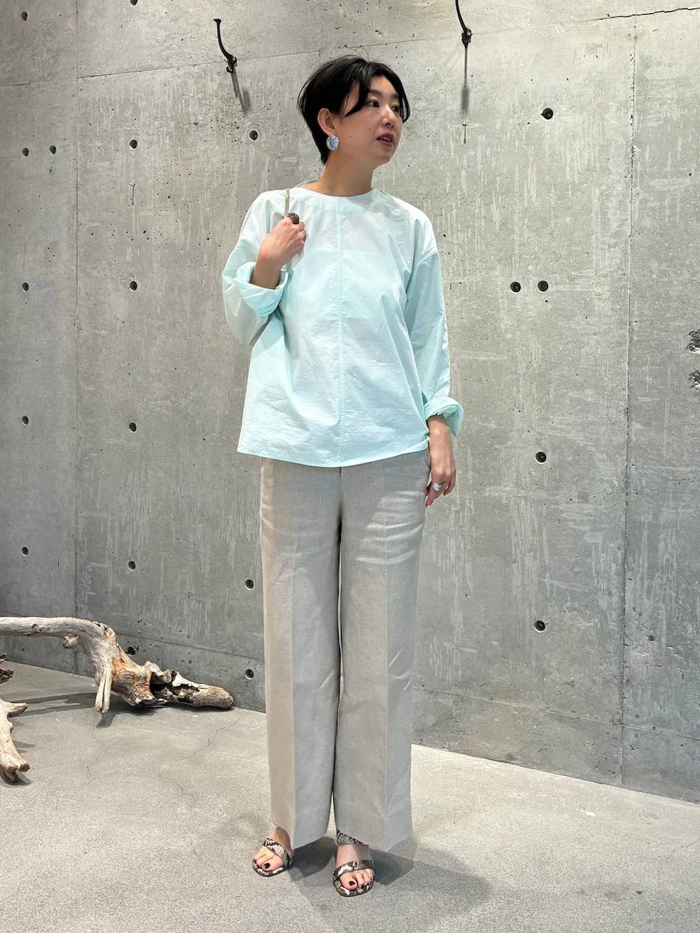 ホワイト系のスラックス、グレー系のナイロンジャケットを着用したレディースの春コーディネートの4枚目の写真