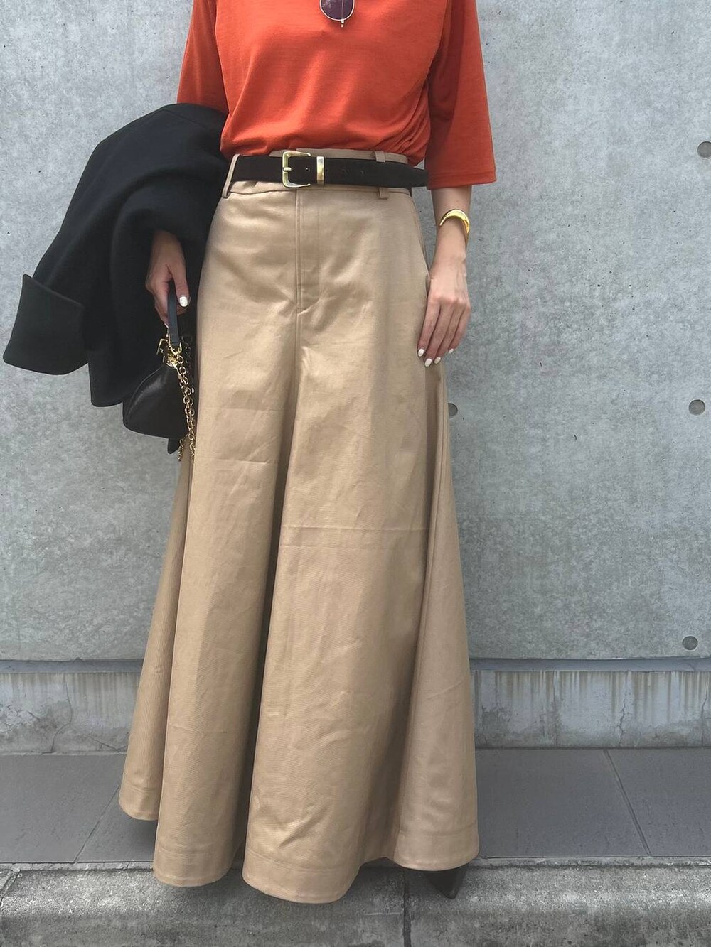 オレンジ系のTシャツ/カットソー、ベージュ系のスカート、ブラック系のその他アウターを着用したレディースの秋コーディネートの8枚目の写真