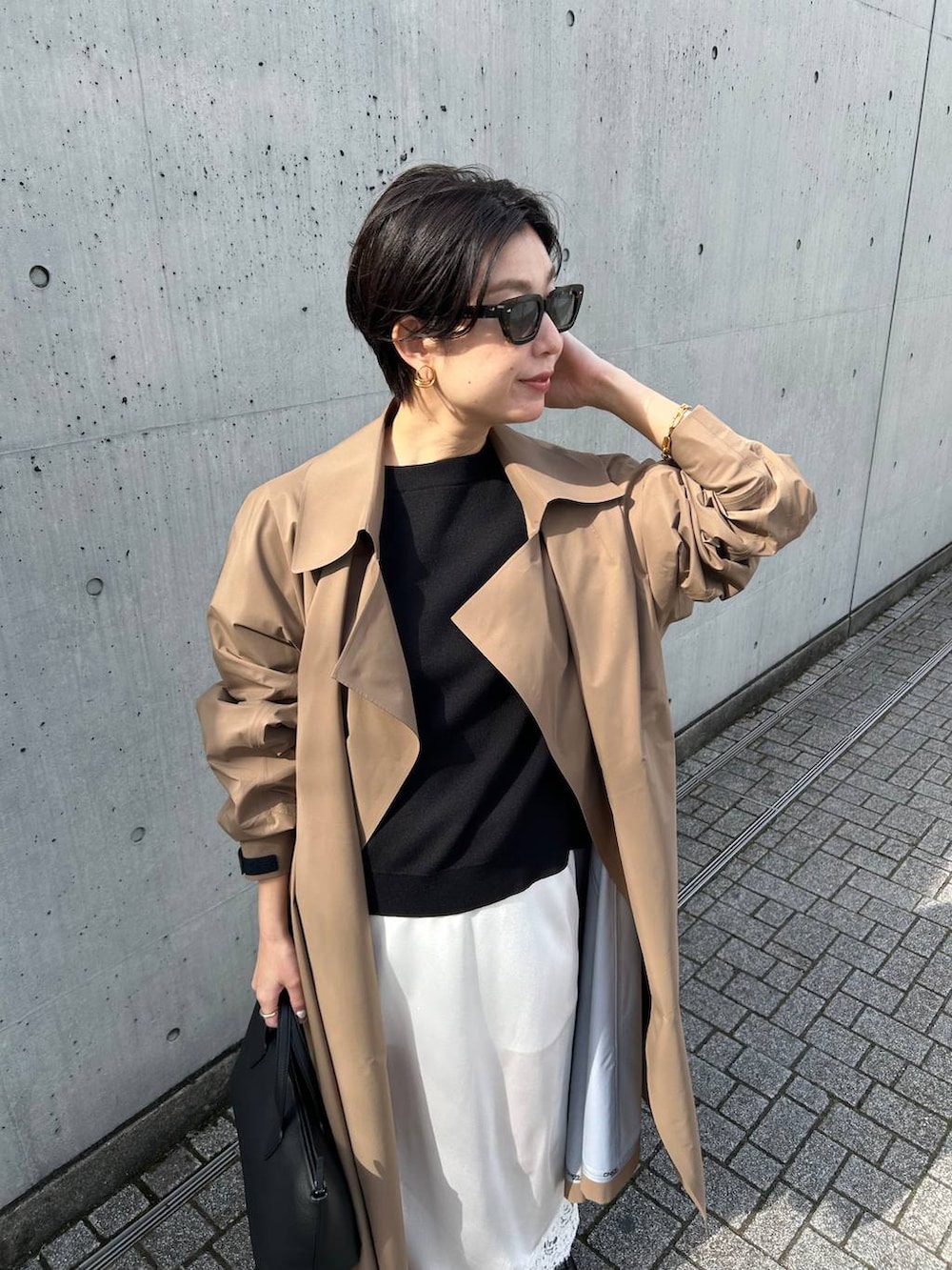 ブラック系のニット/セーター、ベージュ系のトレンチコートを着用したレディースの冬コーディネートの6枚目の写真