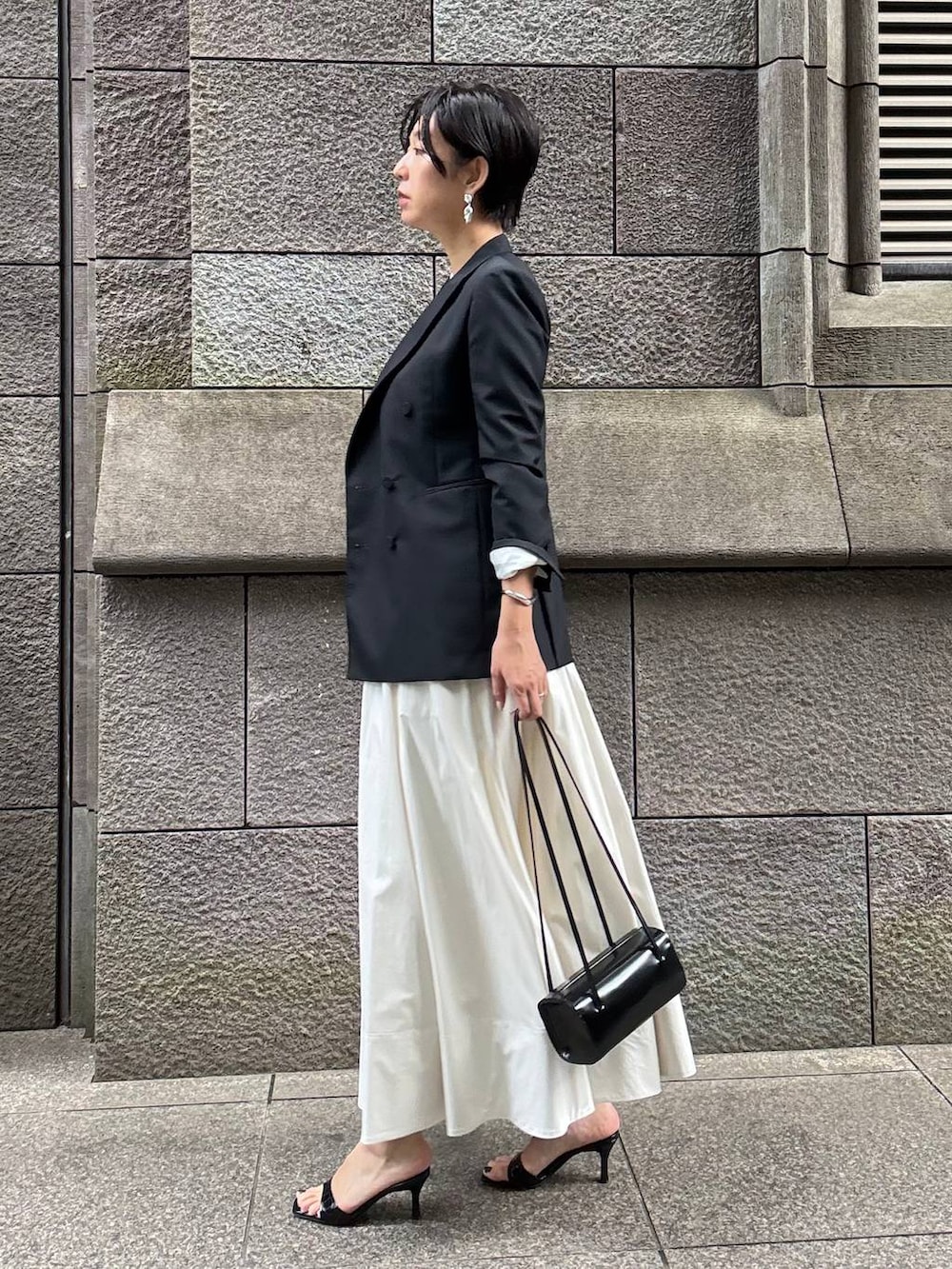 ベージュ系のスカート、ホワイト系のTシャツ/カットソー、ブラック系のテーラードジャケットを着用したレディースの夏コーディネートの3枚目の写真