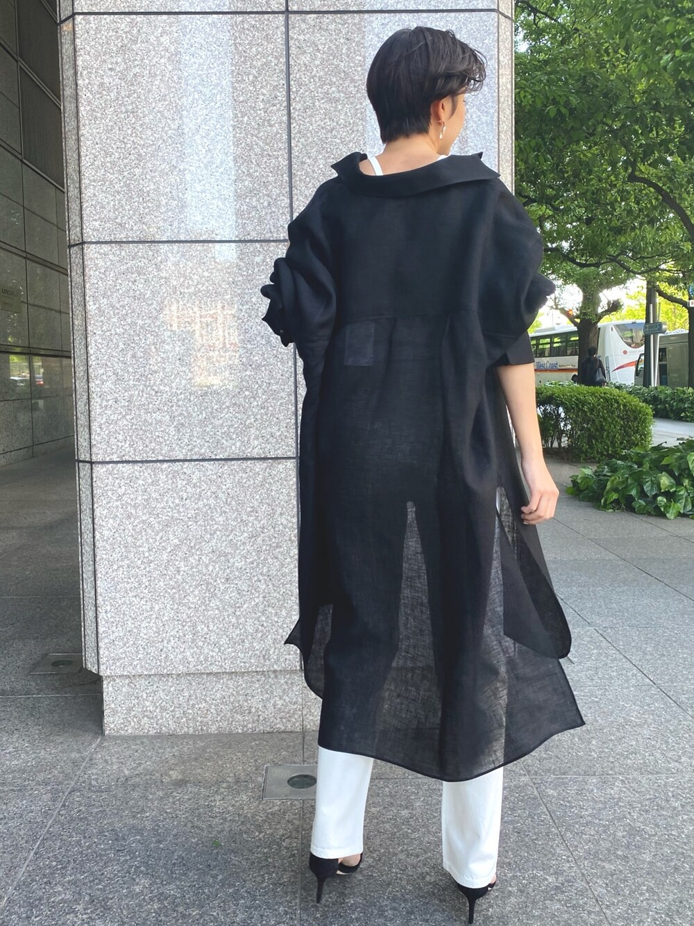 ブラック系のシャツワンピース、ホワイト系のキャミソール、ホワイト系のデニムパンツを着用したレディースの春コーディネートの4枚目の写真