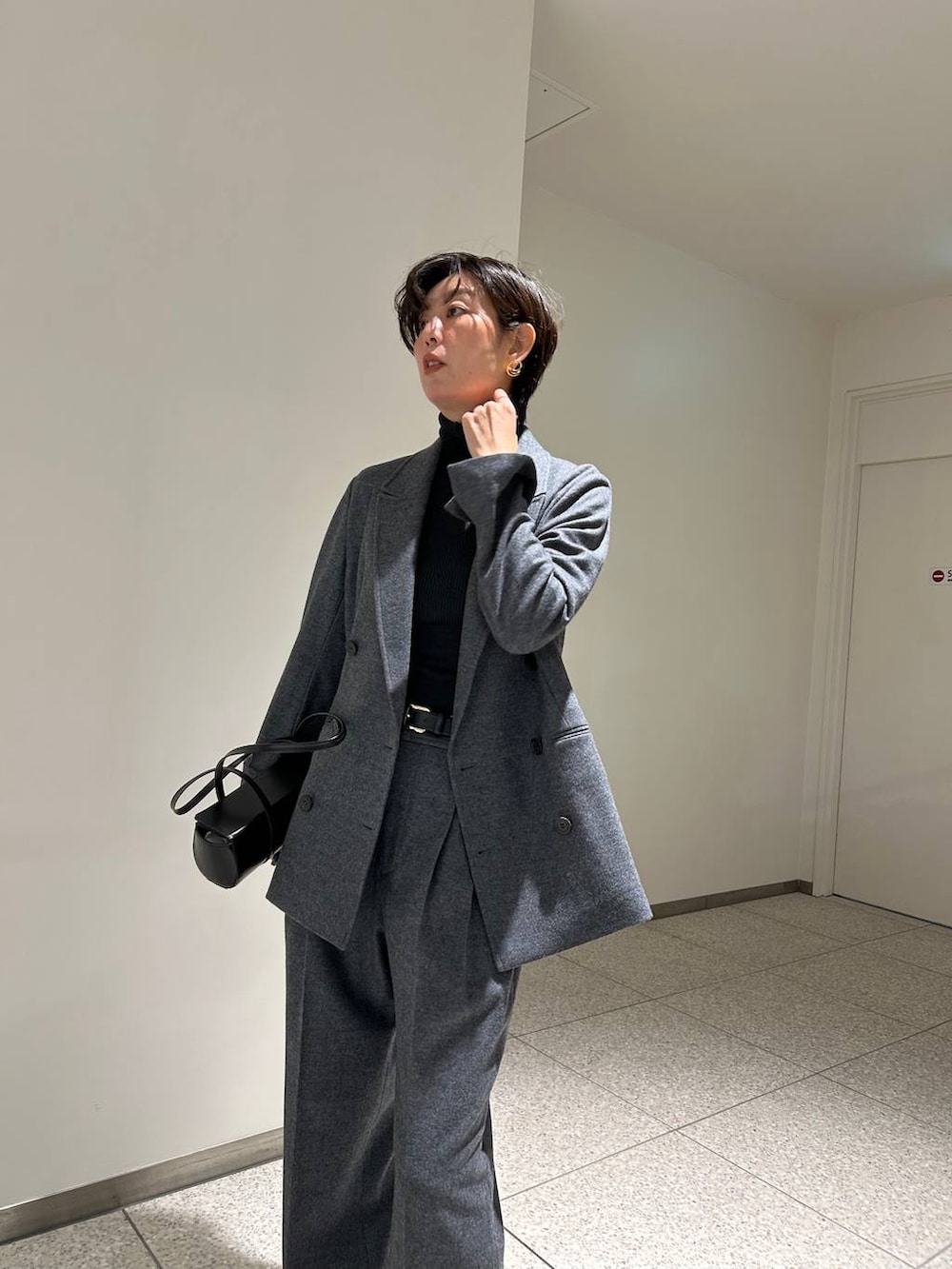 ブラック系のニット/セーター、ブラック系のトレンチコート、グレー系のスラックスを着用したレディースの秋コーディネートの6枚目の写真