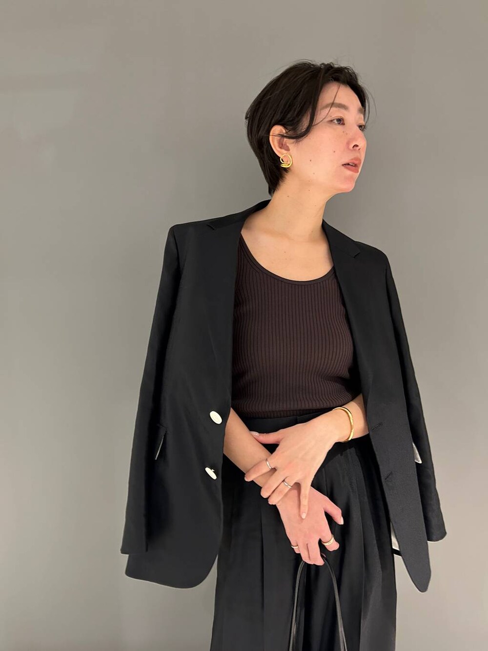 ブラック系のスラックス、ブラック系のテーラードジャケットを着用したレディースの春コーディネートの5枚目の写真