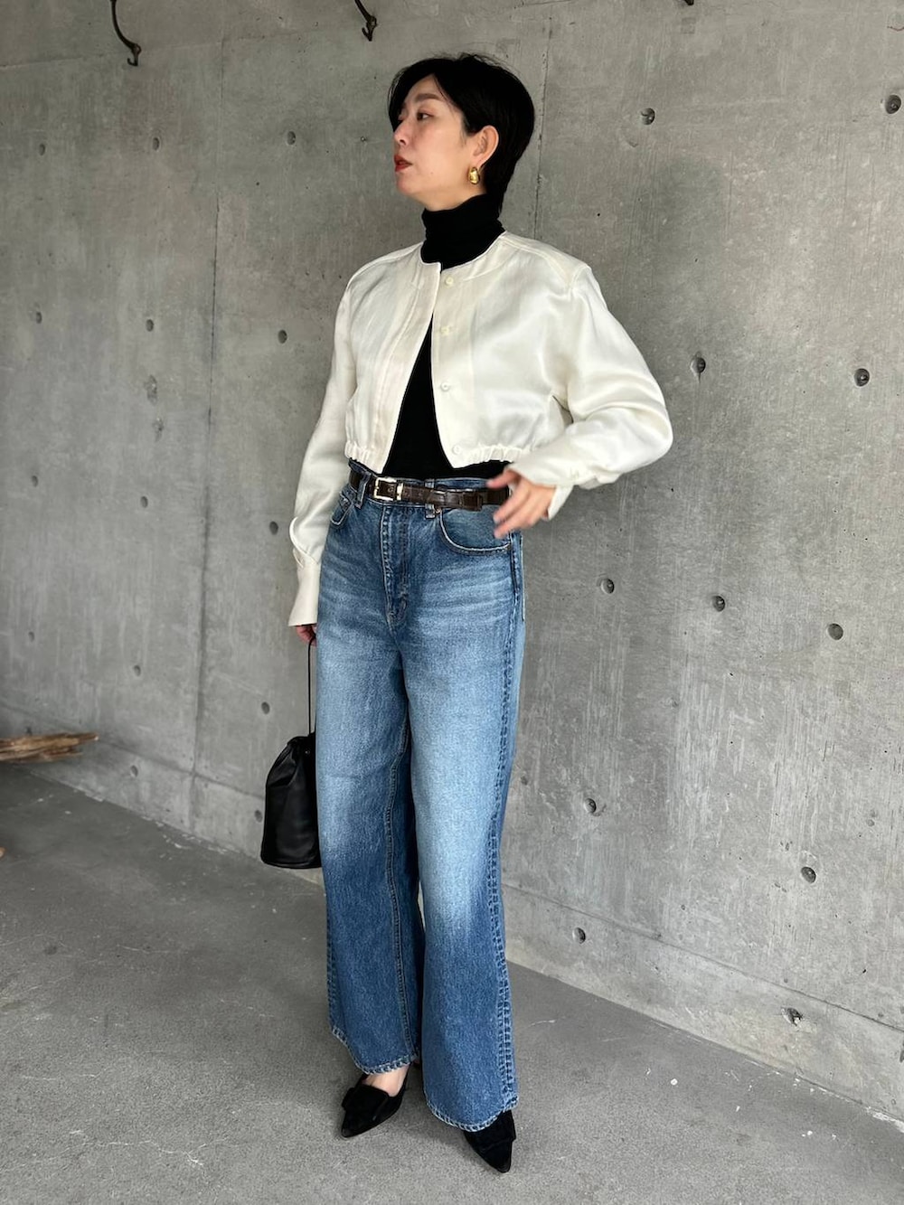 ブラック系のニット/セーター、ブルー系のデニムパンツ、ホワイト系のシャツ/ブラウスを着用したレディースの冬コーディネートの2枚目の写真