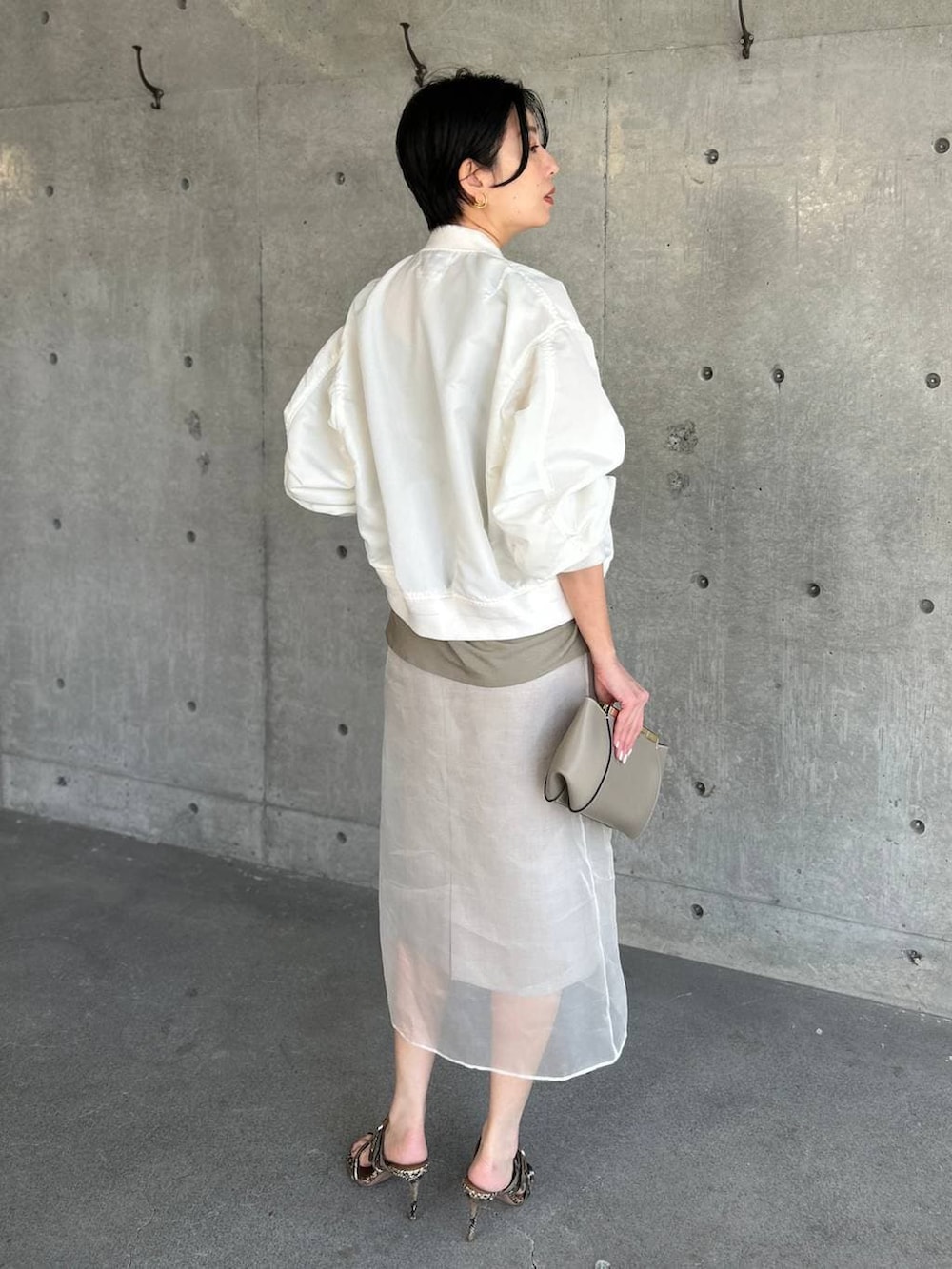 ベージュ系のスカート、ホワイト系のMA-1を着用したレディースの春コーディネートの4枚目の写真