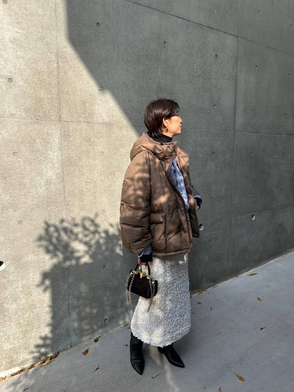 ブラック系のニット/セーター、ブルー系のシャツ/ブラウス、ブラウン系のダウンジャケット/コートを着用したレディースの冬コーディネートの6枚目の写真