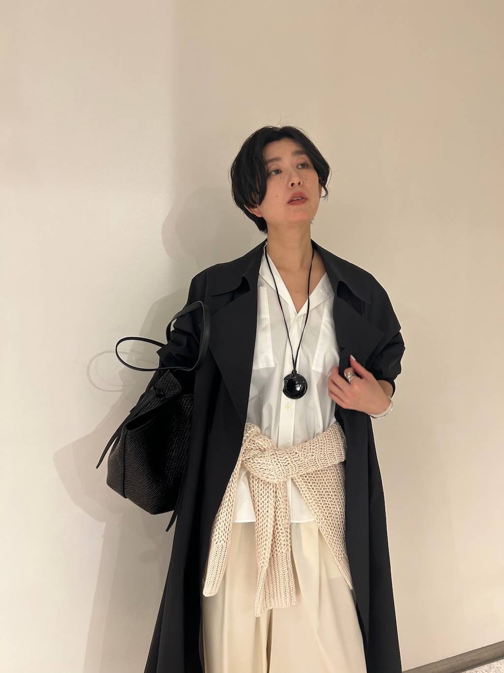 ホワイト系のニット/セーター、ホワイト系のシャツ/ブラウス、ブラック系のトレンチコートを着用したレディースの冬コーディネートの4枚目の写真