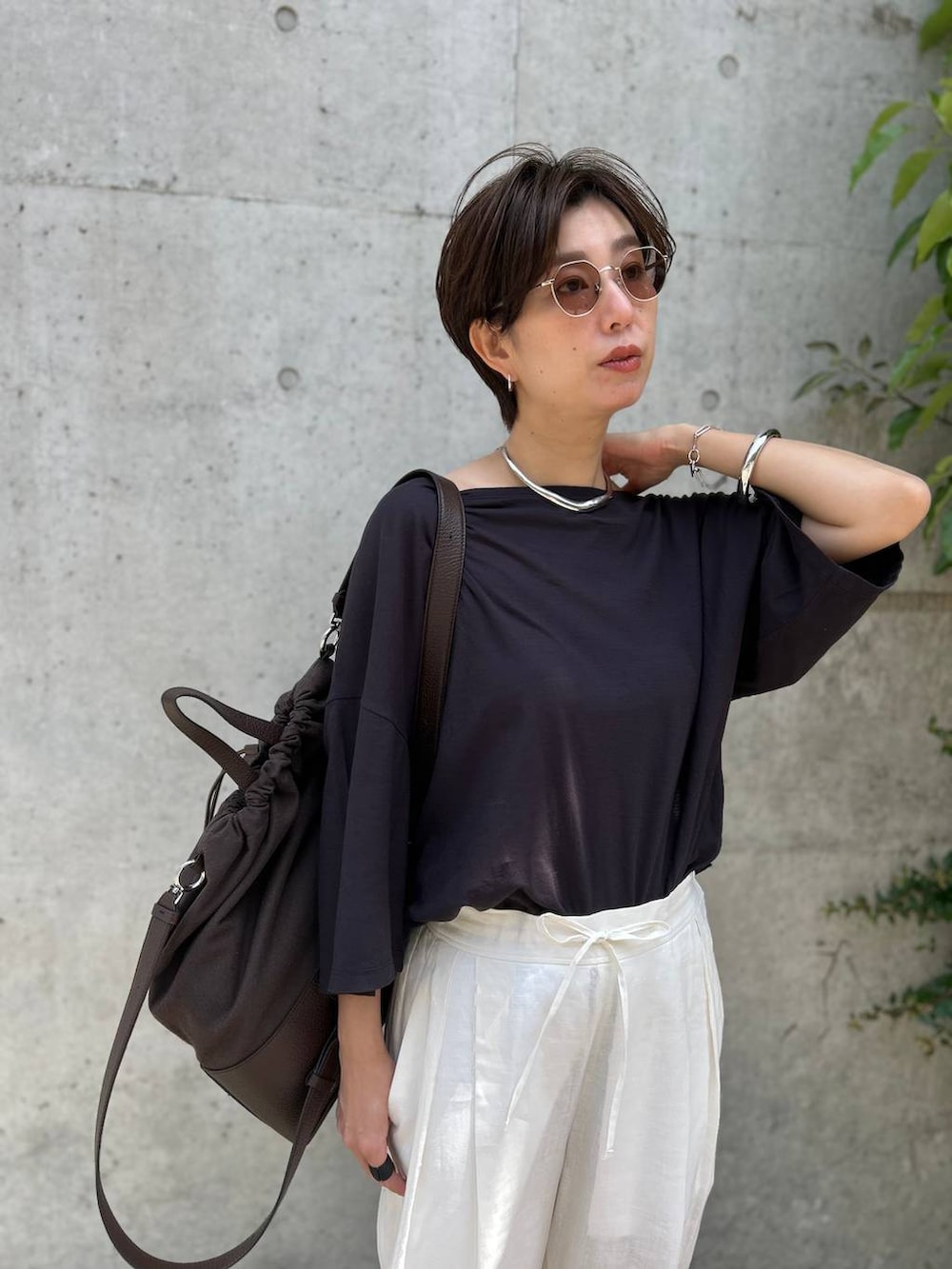 ブラック系のチューブトップ、ホワイト系のスラックス、グレー系のTシャツ/カットソーを着用したレディースの春コーディネートの5枚目の写真