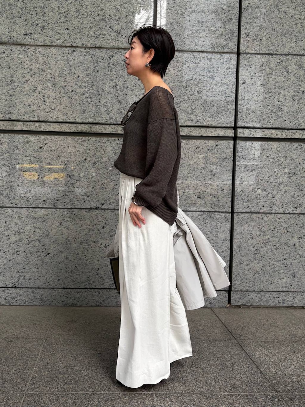 グリーン系のニット/セーター、ホワイト系のスラックス、グレー系のナイロンジャケットを着用したレディースの春コーディネートの5枚目の写真