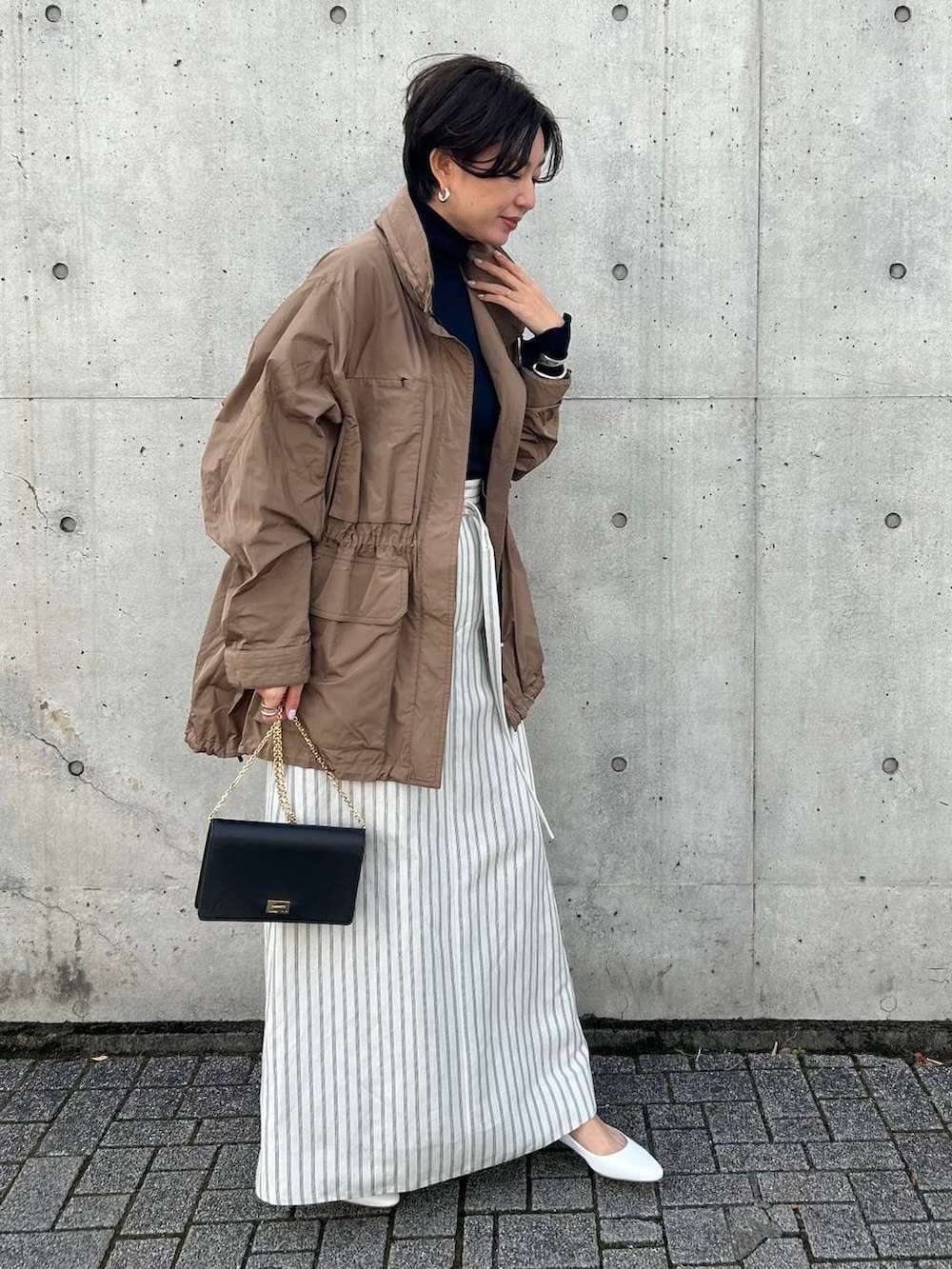 ブルー系のニット/セーター、ホワイト系のスカート、ベージュ系のブルゾンを着用したレディースの冬コーディネートの2枚目の写真