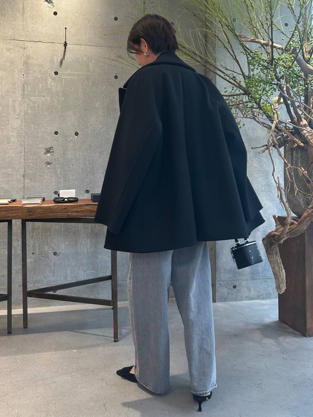 グレー系のデニムパンツ、ブラック系のピーコート、シルバー系のニット/セーターを着用したレディースの秋コーディネートの5枚目の写真
