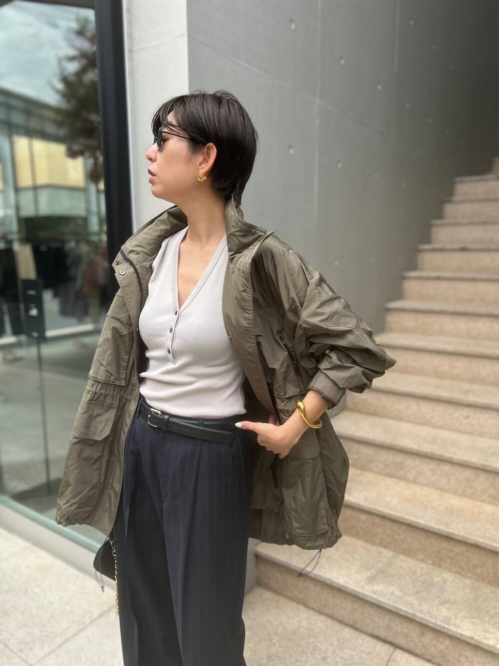 グレー系のTシャツ/カットソー、グリーン系のブルゾン、ブルー系のスラックスを着用したレディースの夏コーディネートの6枚目の写真