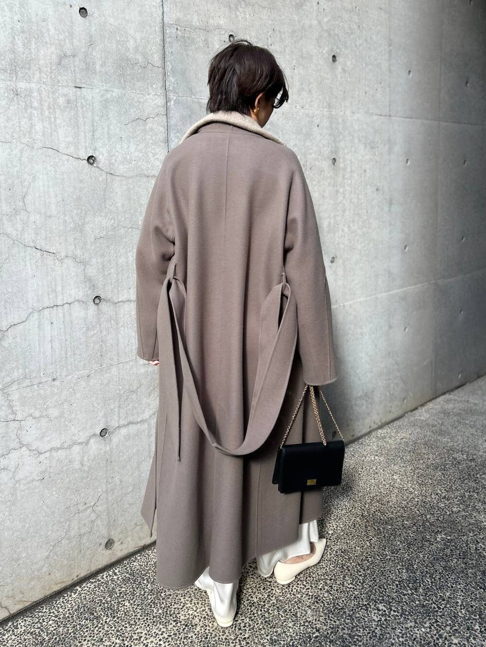 ブラウン系のノーカラーコート、ホワイト系のその他パンツ、ベージュ系のニット/セーターを着用したレディースの冬コーディネートの4枚目の写真