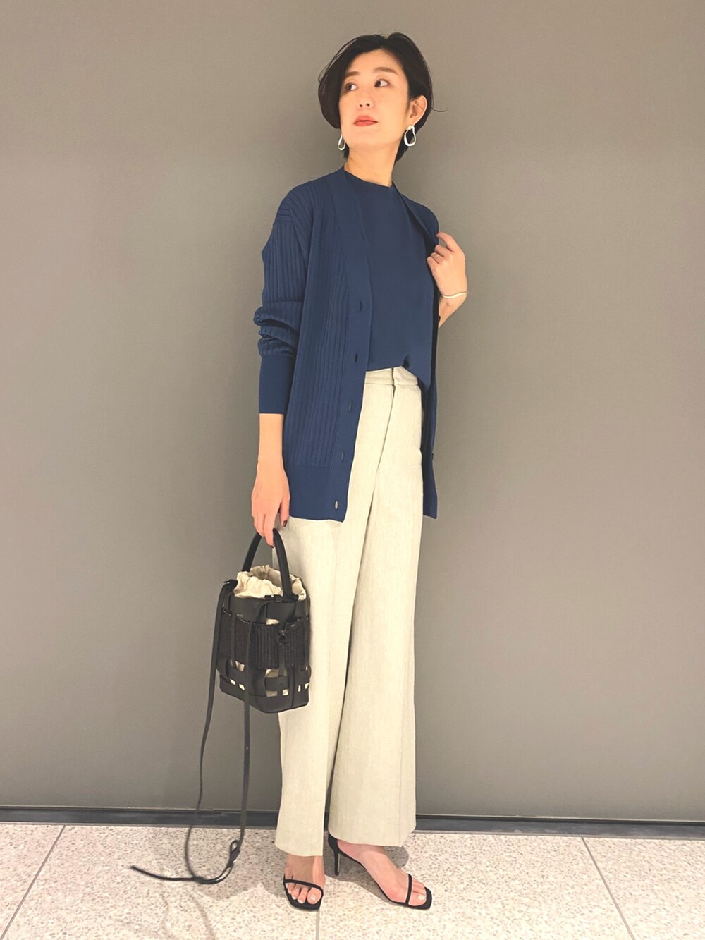 ブルー系のカーディガン/ボレロ、ブルー系のニット/セーター、グレー系のスラックスを着用したレディースの春コーディネートの5枚目の写真