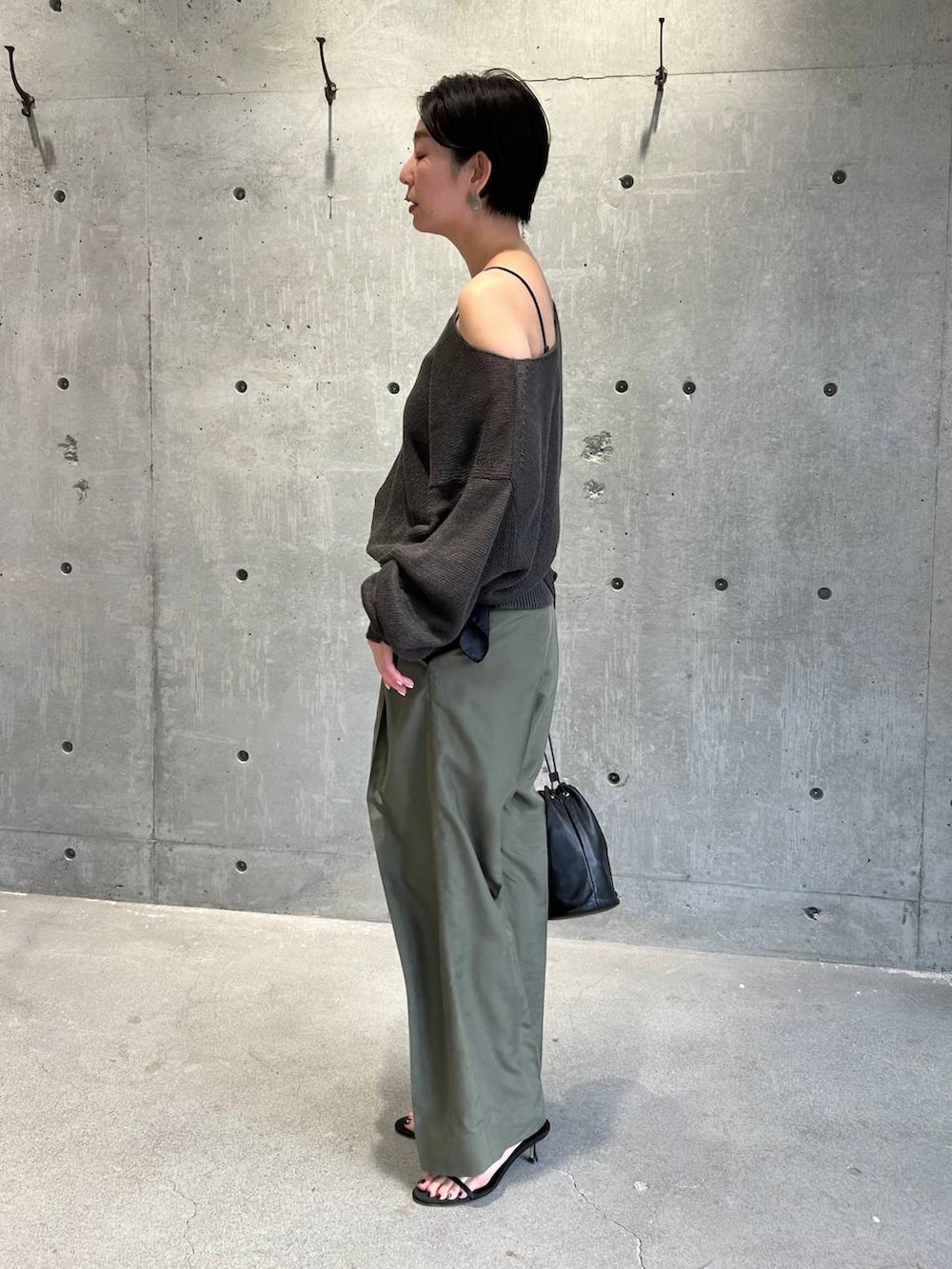 ブラック系のチューブトップ、グリーン系のニット/セーター、グリーン系のスラックスを着用したレディースの春コーディネートの3枚目の写真