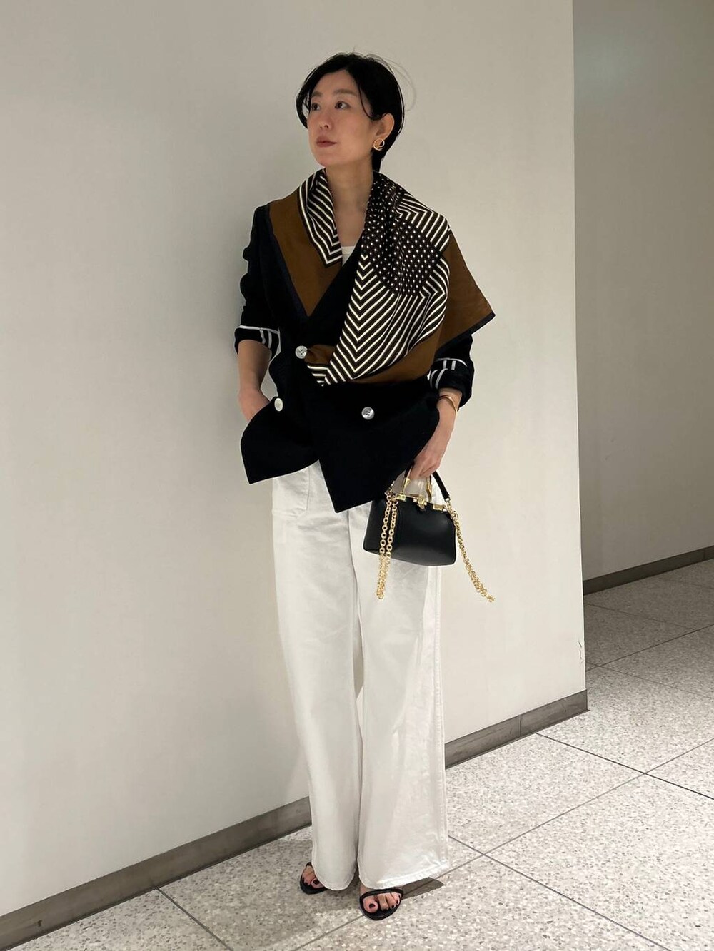 ホワイト系のデニムパンツ、ホワイト系のタンクトップ、ブラック系のテーラードジャケットを着用したレディースの春コーディネートの2枚目の写真